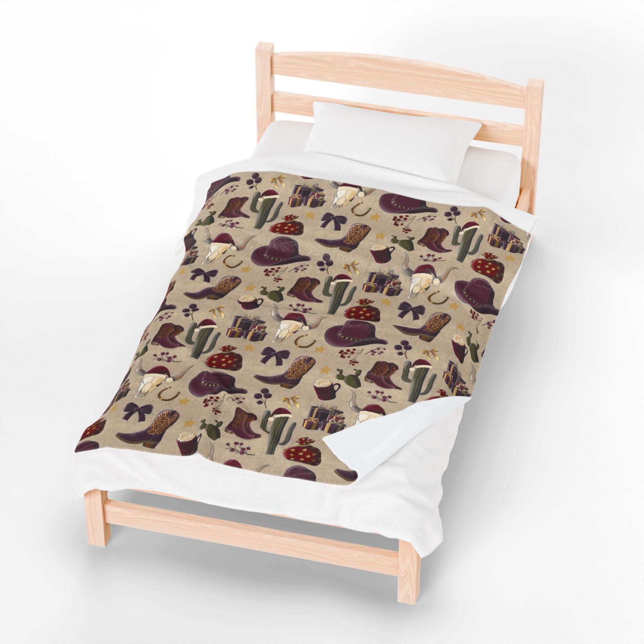 Plush blanket with cowboy Christmas design featuring hats, boots, cacti, and festive elements on a beige background, soft velveteen fabric.