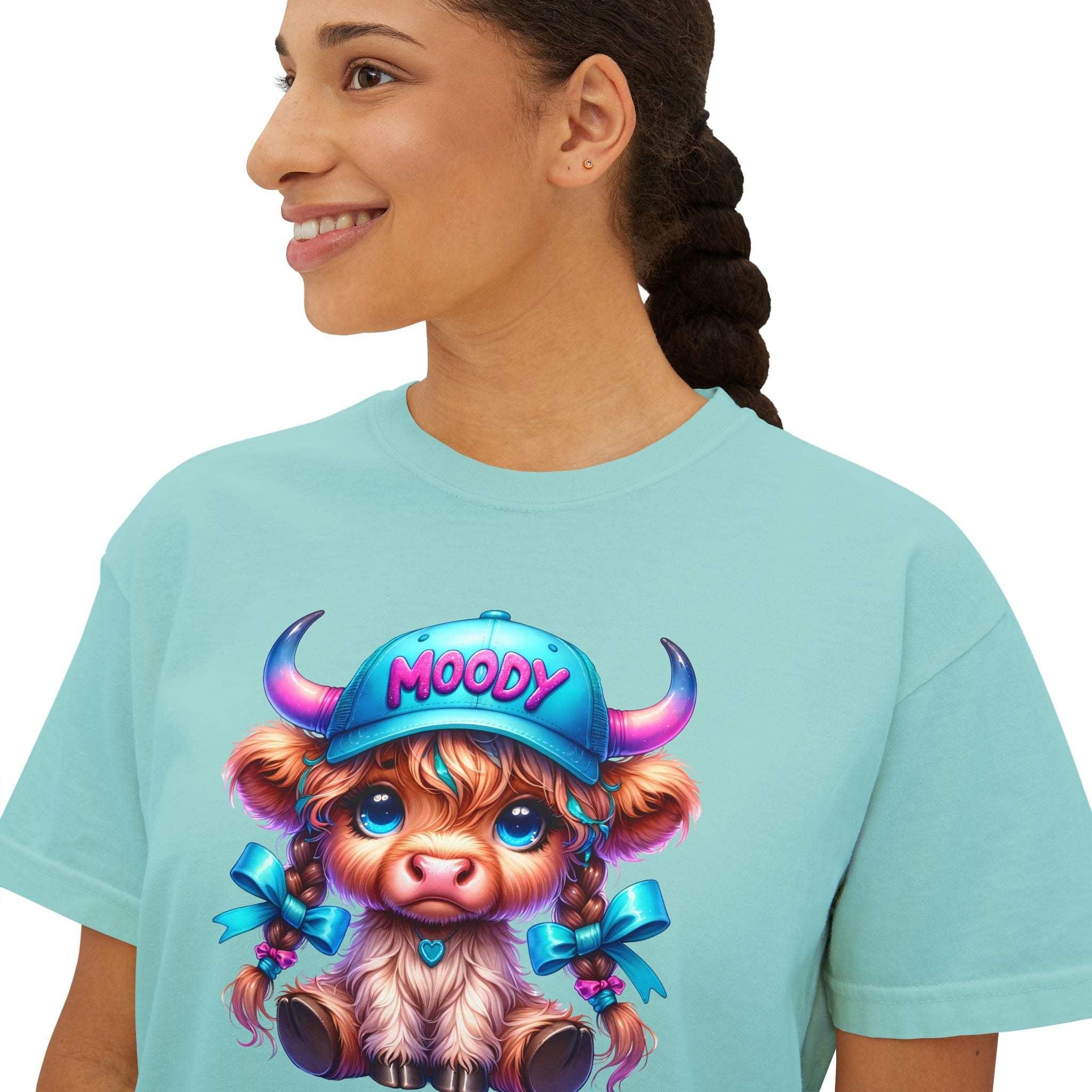 Woman wearing light blue boxy tee with moody girl highland cow graphic design