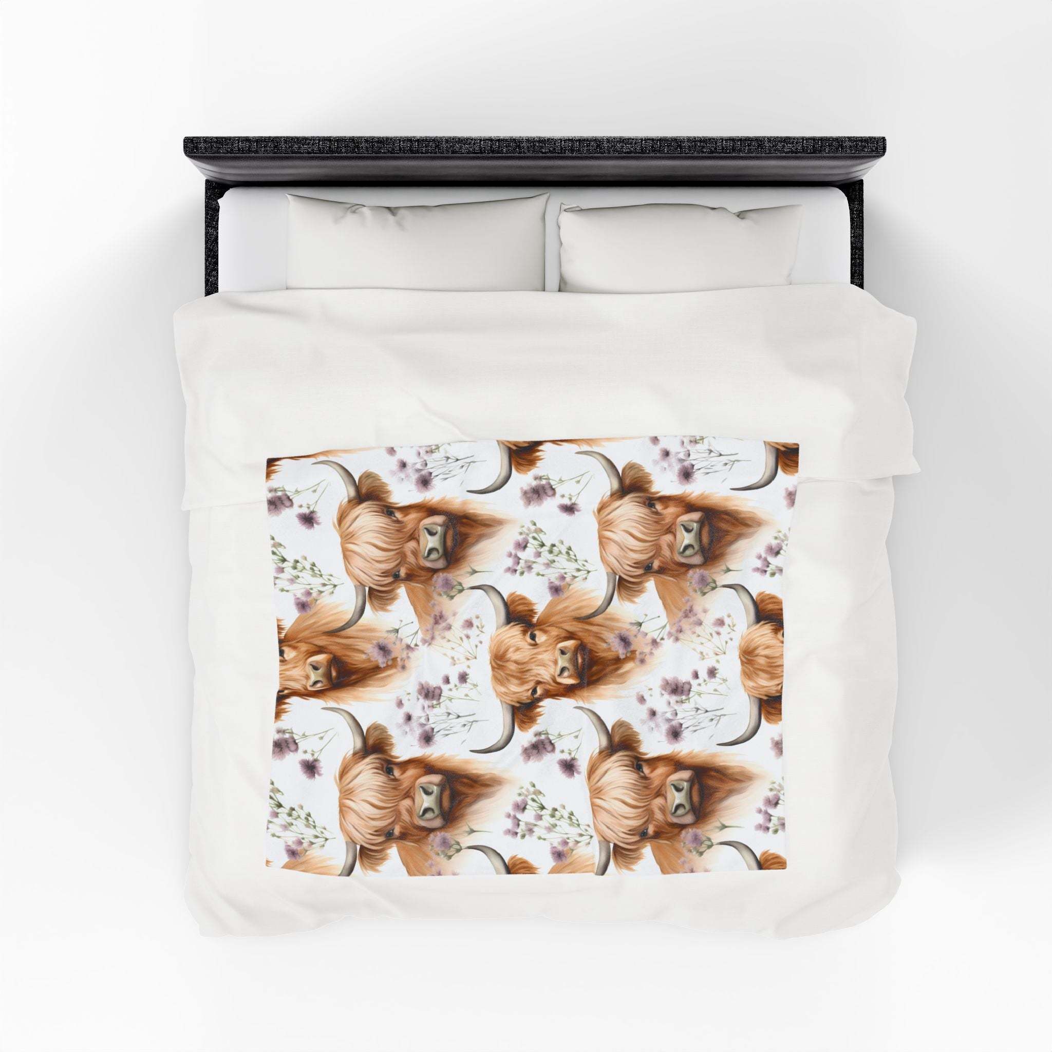 Plush blanket with floral highland cow design on white bed covering