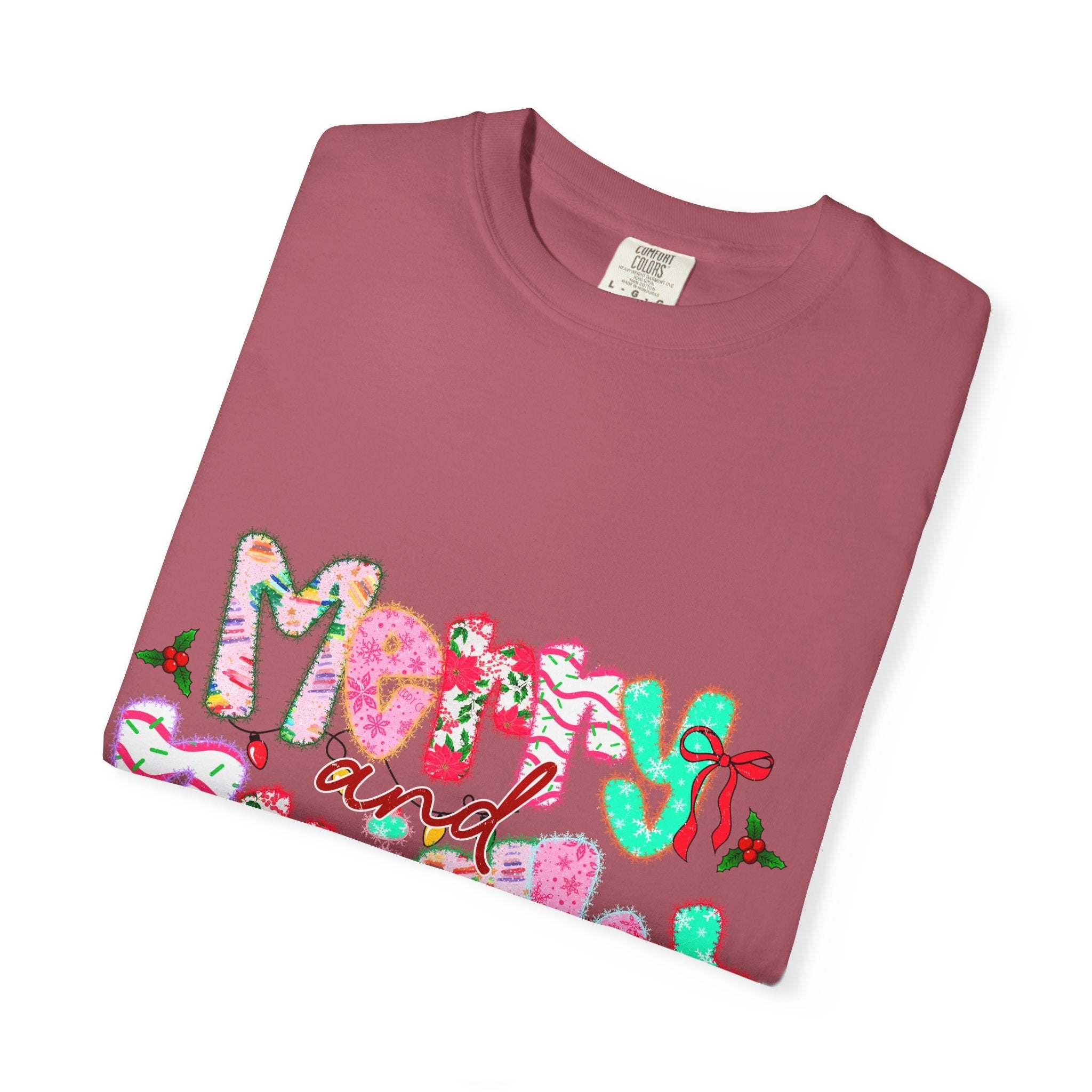 Folded Merry and Bright T-shirt in festive red with colorful holiday lettering and holly accents