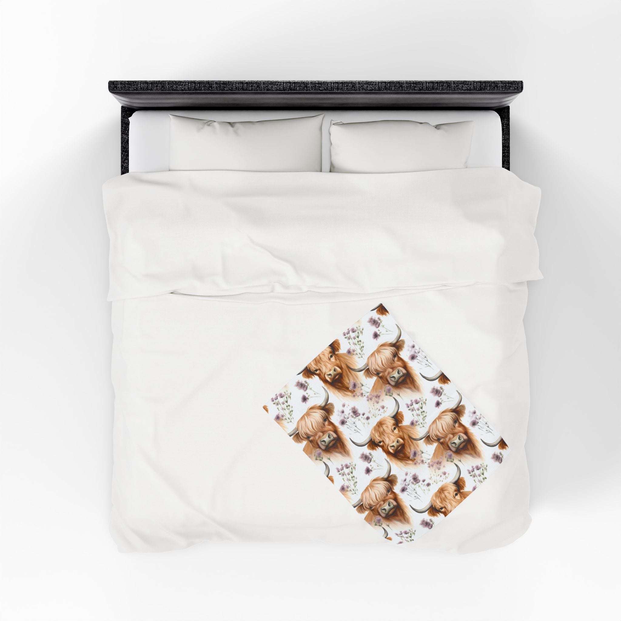 Plush blanket with floral Highland cow design on white bedding