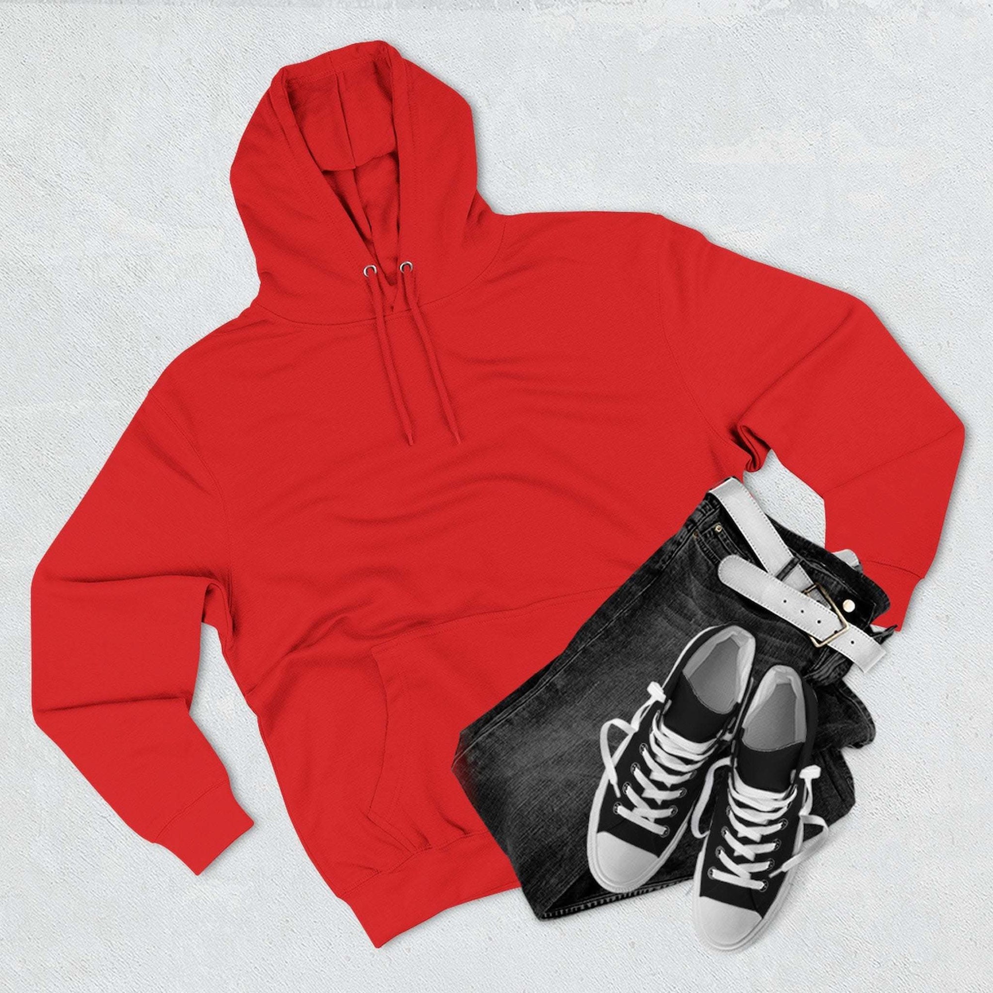 Red fleece hoodie with kangaroo pocket, paired with black jeans and black sneakers, flat lay on white background