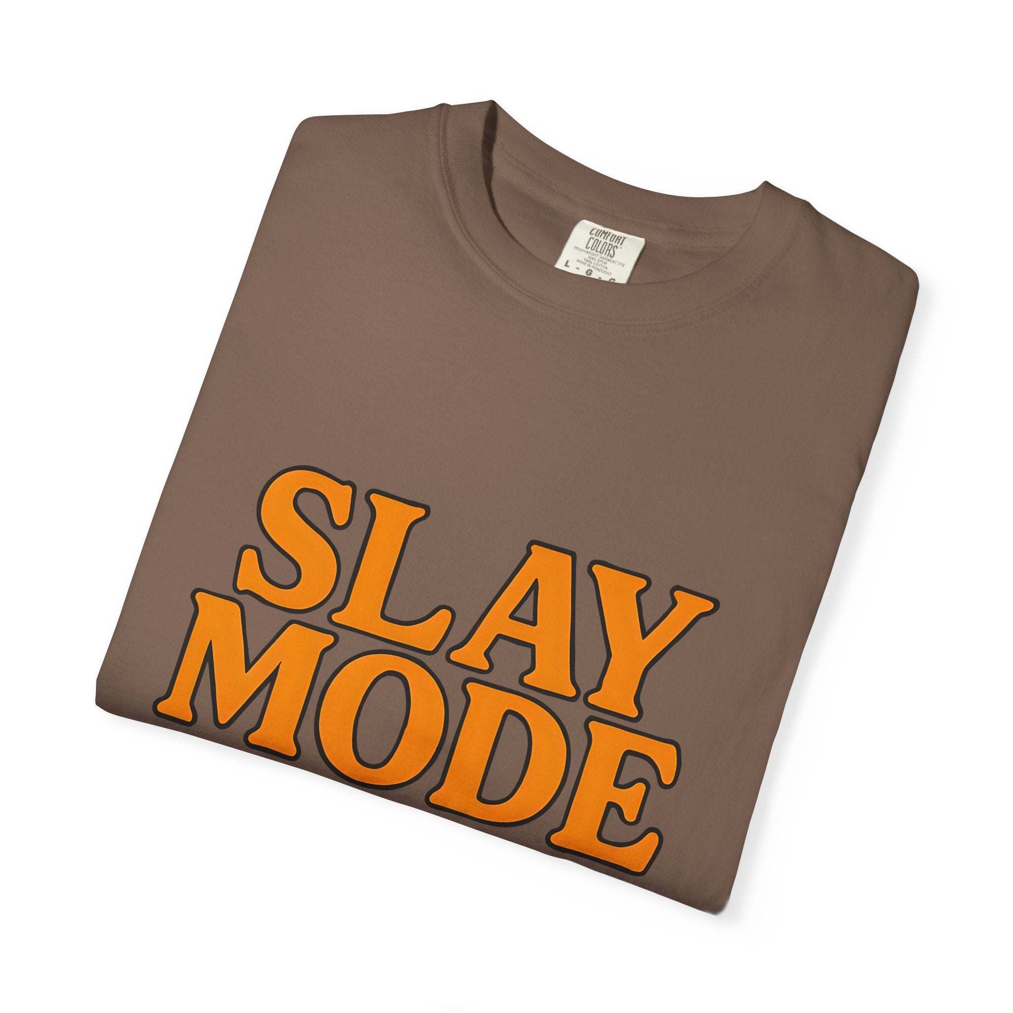 Folded brown garment-dyed tee with bold orange "SLAY MODE" text on front