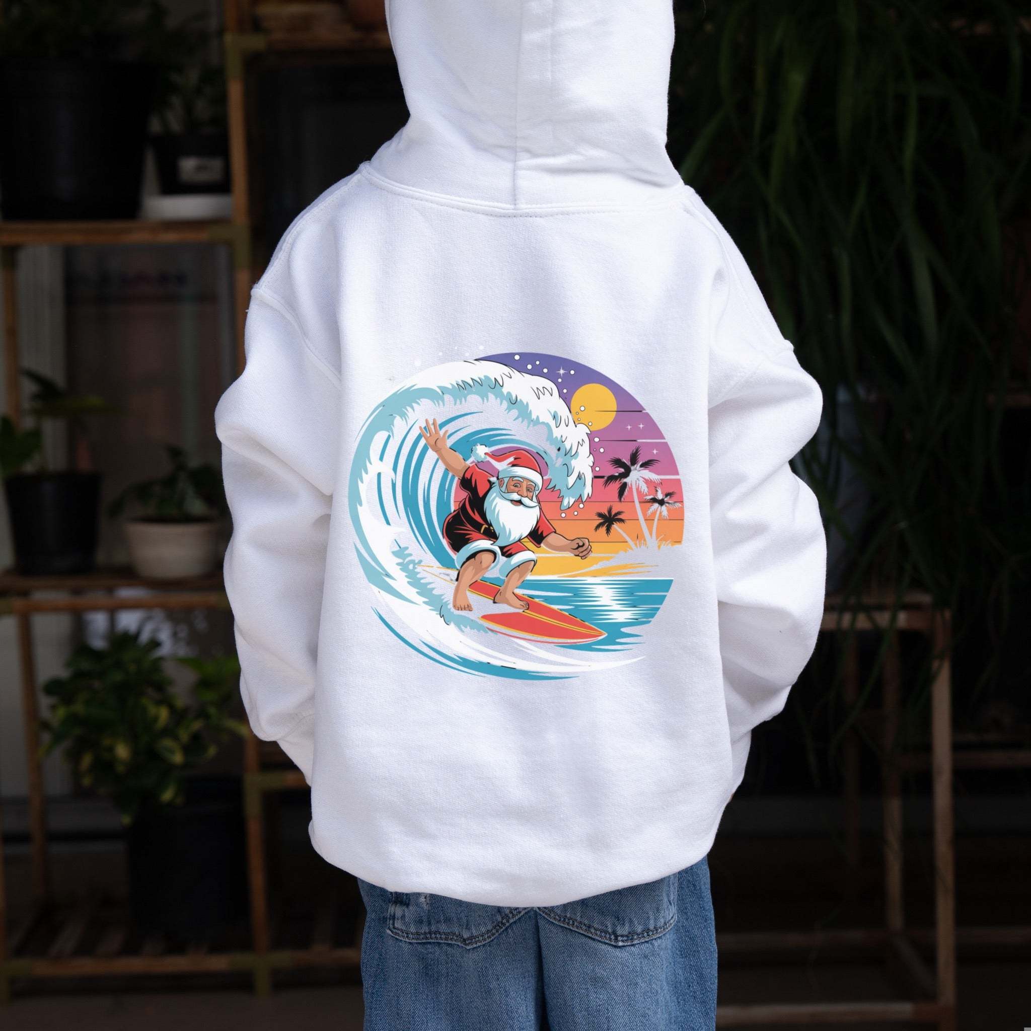 Child wearing white Surfing Santa Hoodie with festive Santa surfing graphic on back