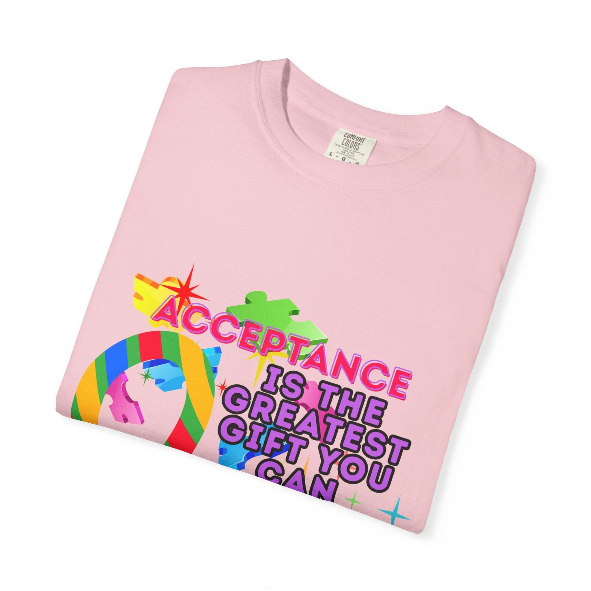Pink garment-dyed T-shirt promoting autism acceptance with colorful puzzle design and inclusive message