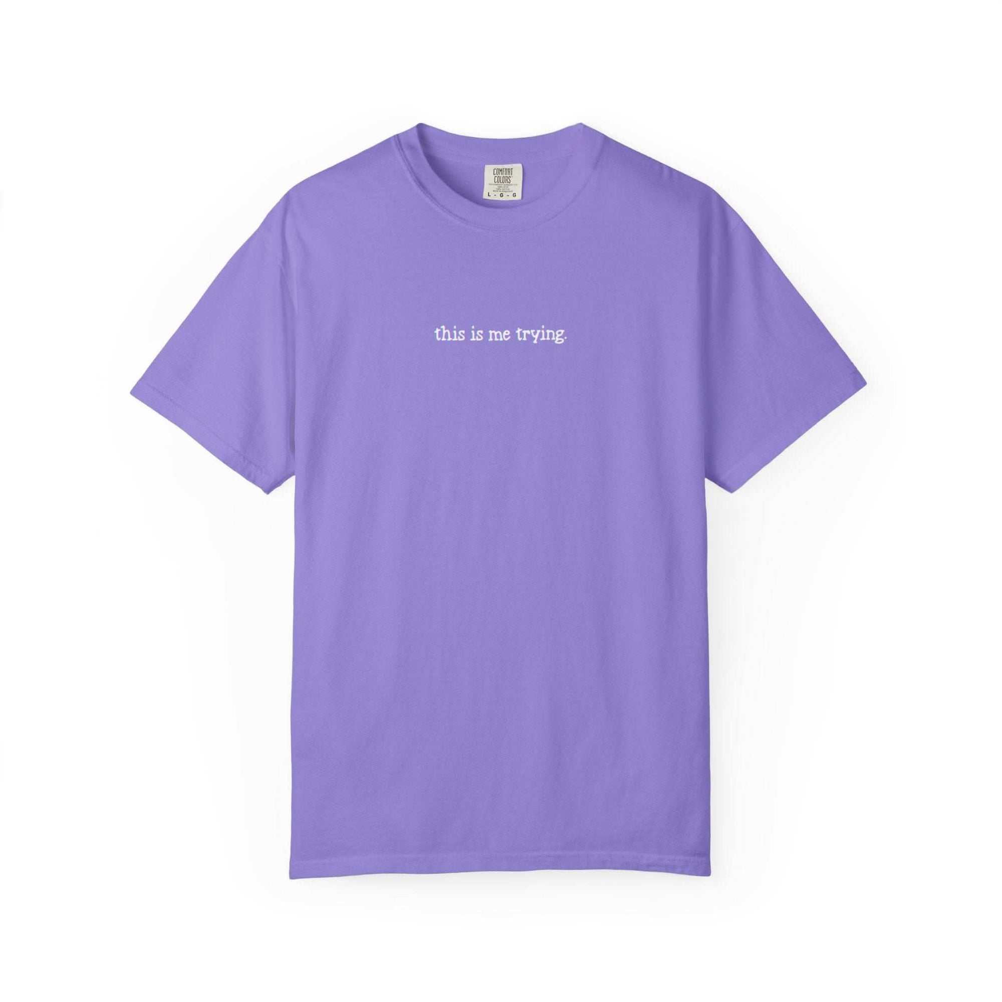 Purple t-shirt with 'this is me trying' text on a white background
