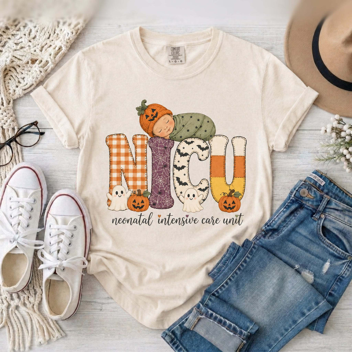 Ivory NICU nurse Halloween T-shirt with patchwork lettering, a sleeping baby in a pumpkin hat, ghosts, and jack-o’-lanterns.
