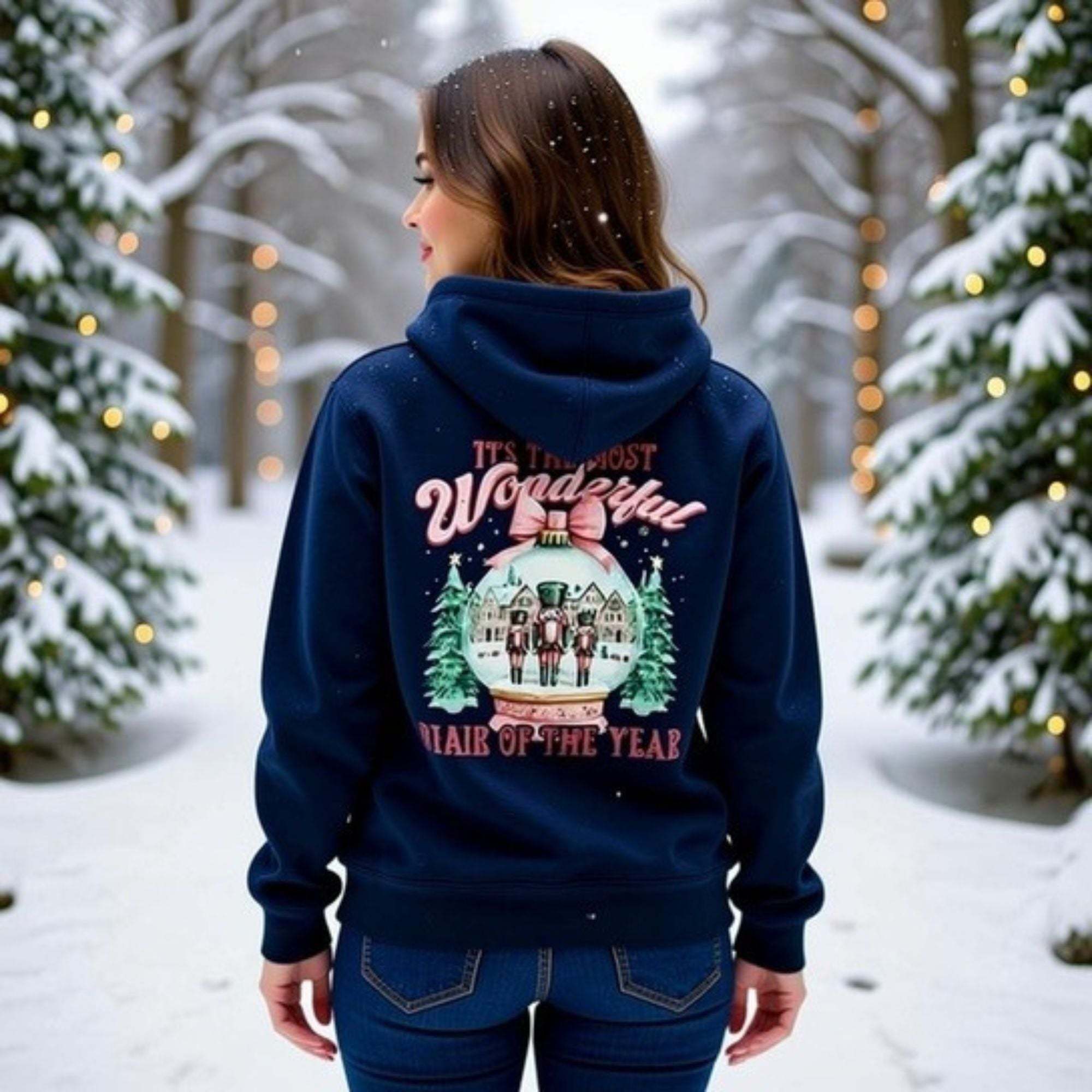 Woman wearing navy fleece hoodie with vintage pink snow globe design in snowy forest