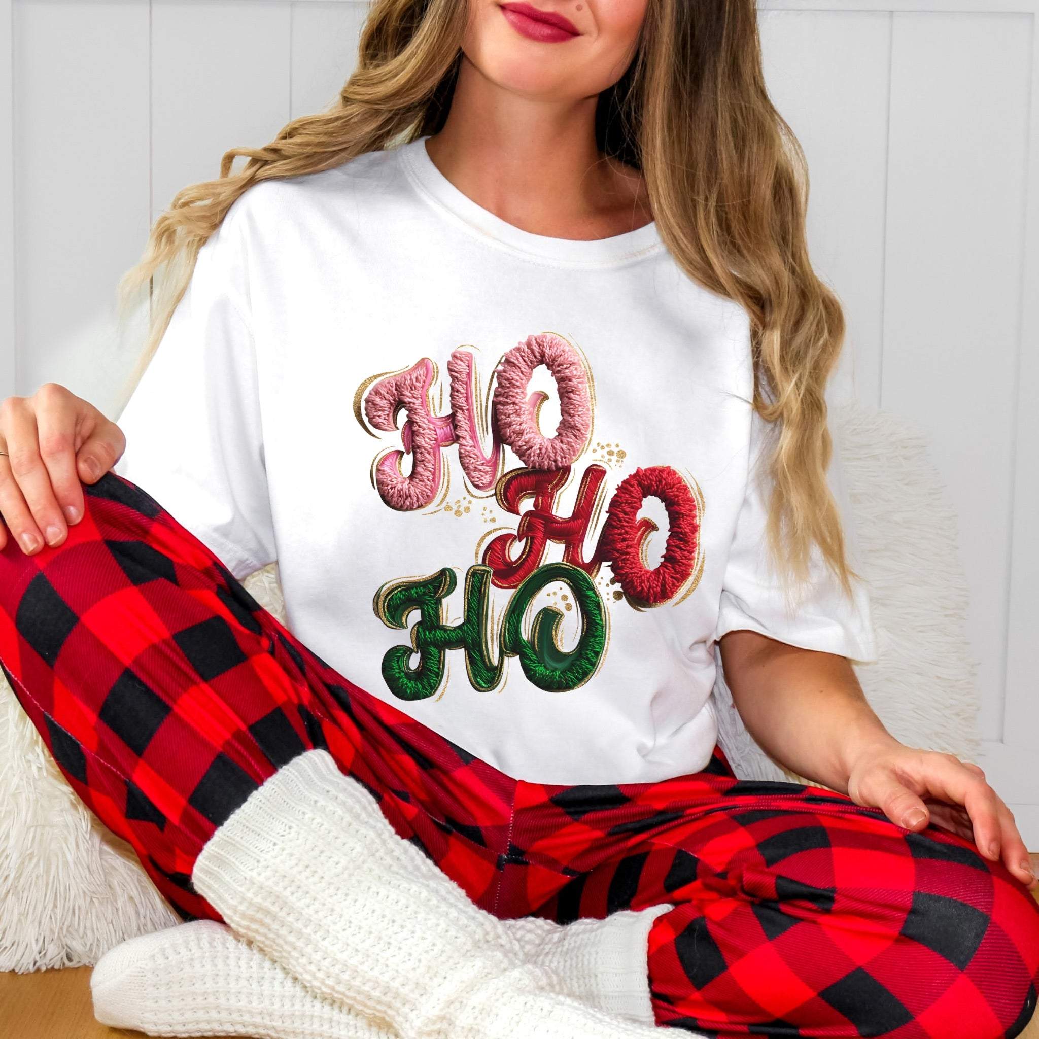 Woman wearing white T-shirt with faux puffy crochet "Ho, Ho, Ho" Christmas design and red plaid pants