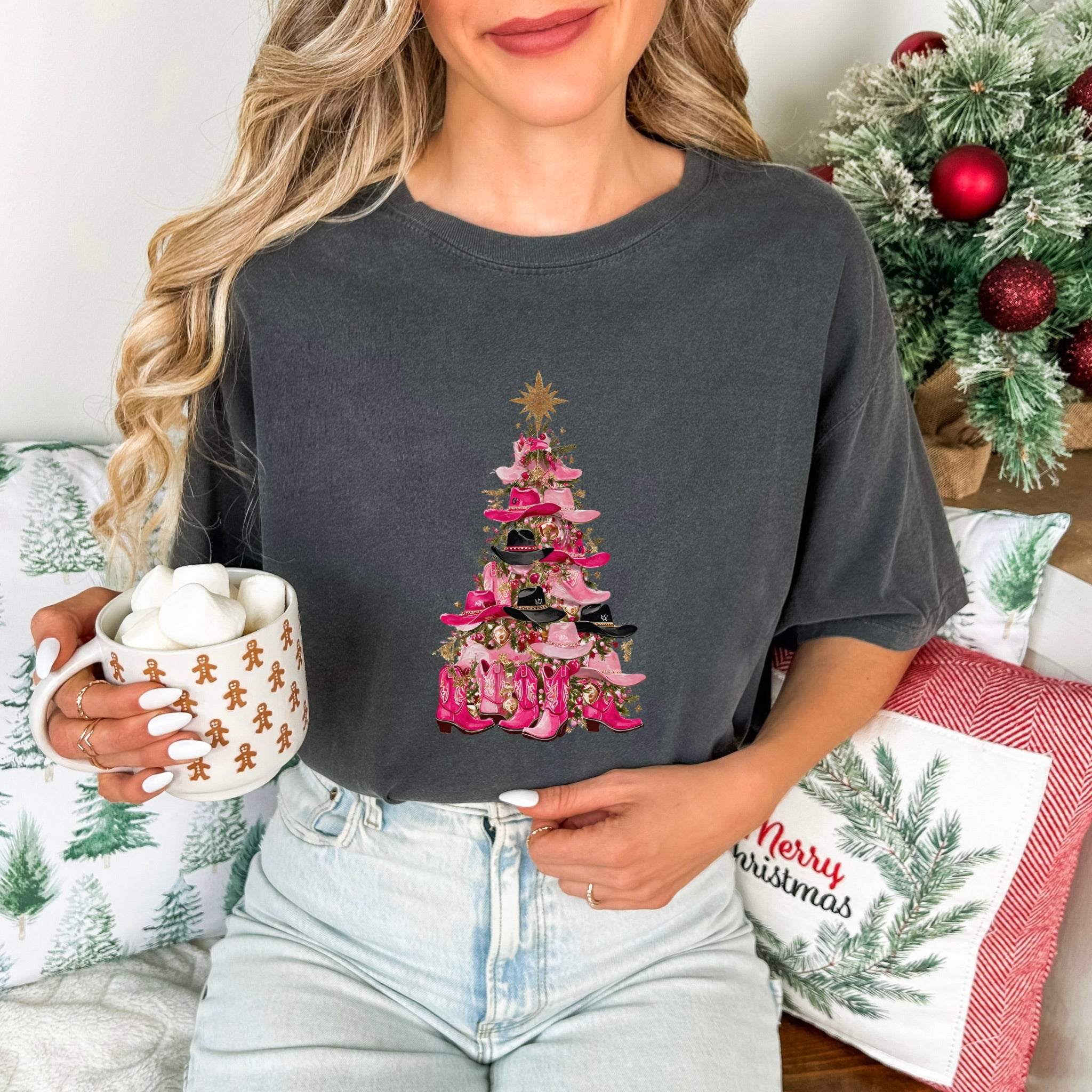 Woman wearing Cowgirl Christmas Tree T-shirt with festive holiday design and holding mug of hot chocolate with marshmallows