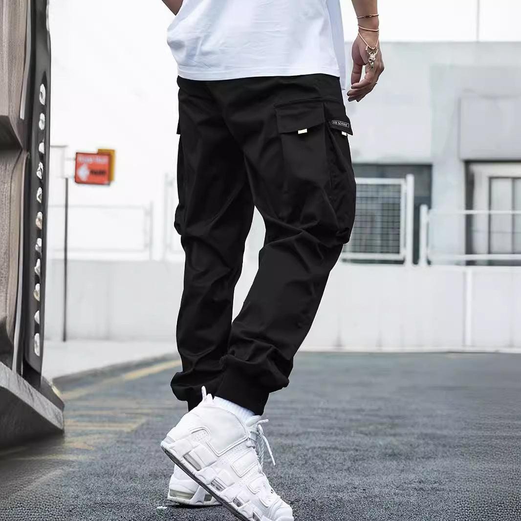 Black multi-pocket cargo pants for men with a casual, loose fit and drawstring waist, styled for outdoor and streetwear activities.