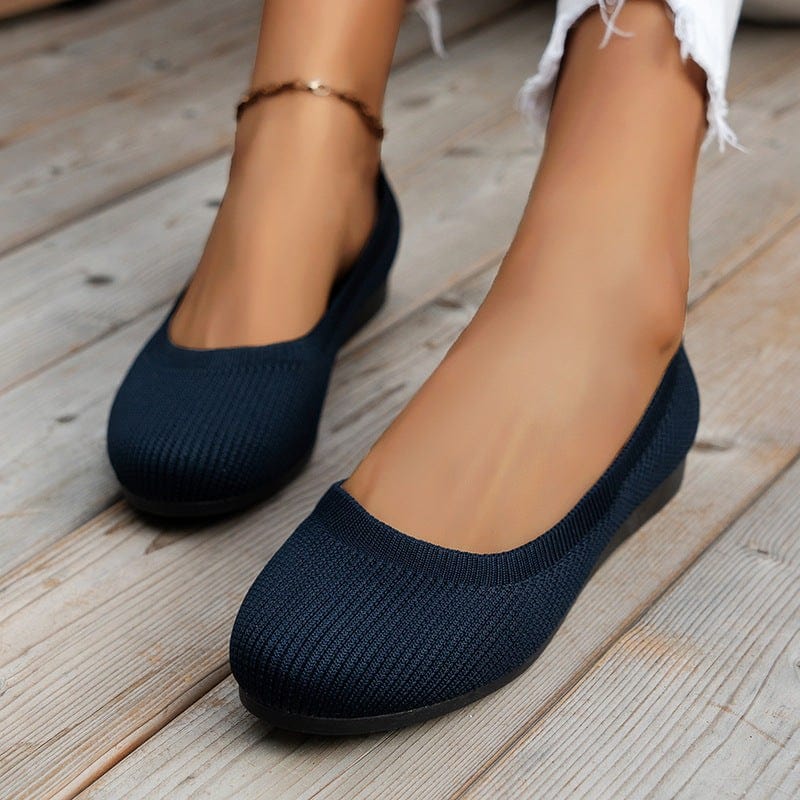 Women's navy blue round toe flats with soft knit mesh upper on wooden floor