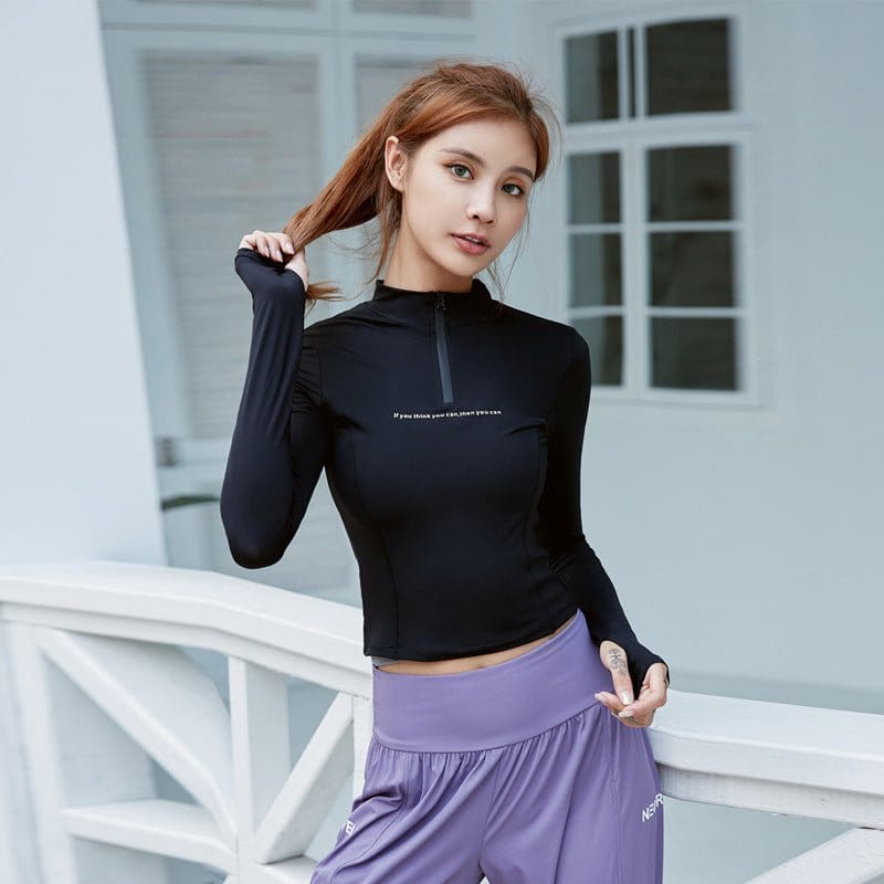 woman wearing black half-zip sports long-sleeved top with stand-up collar and purple workout shorts