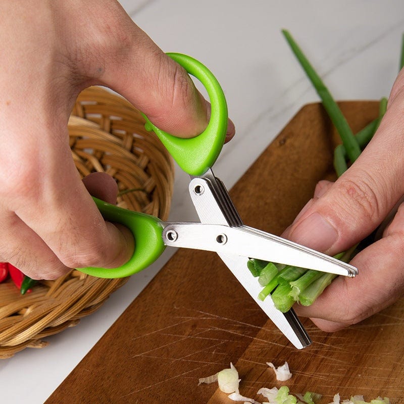 Multifunctional multi-layer green onion scissors with stainless steel blades and green handles cutting fresh green onions on a wooden board