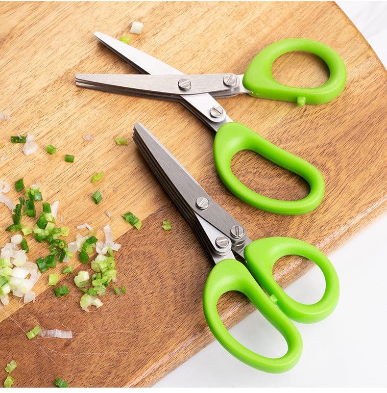 Multifunctional multi-layer green onion scissors with stainless steel blades and green handles cutting chopped onions on a wooden board
