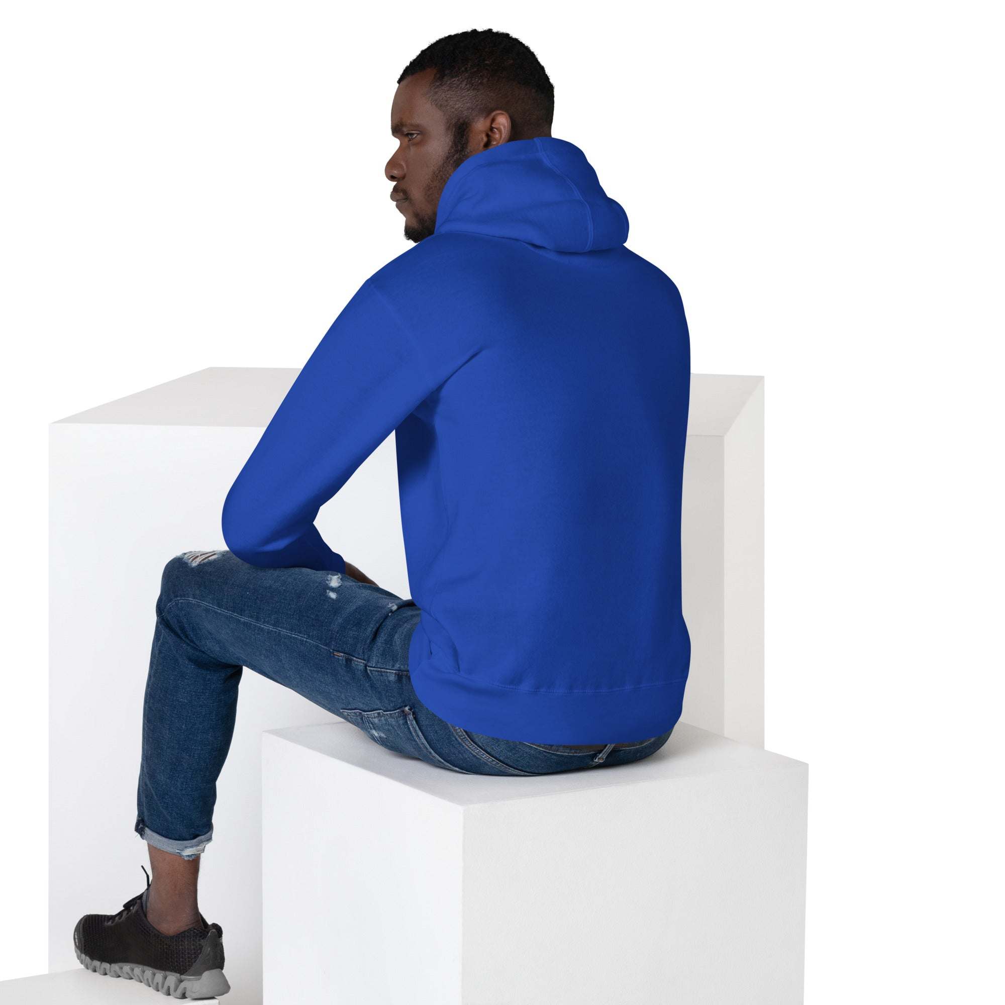 Man wearing blue Basketball Dunk Hoodie sitting on white cube, back view, casual outfit with jeans and sneakers