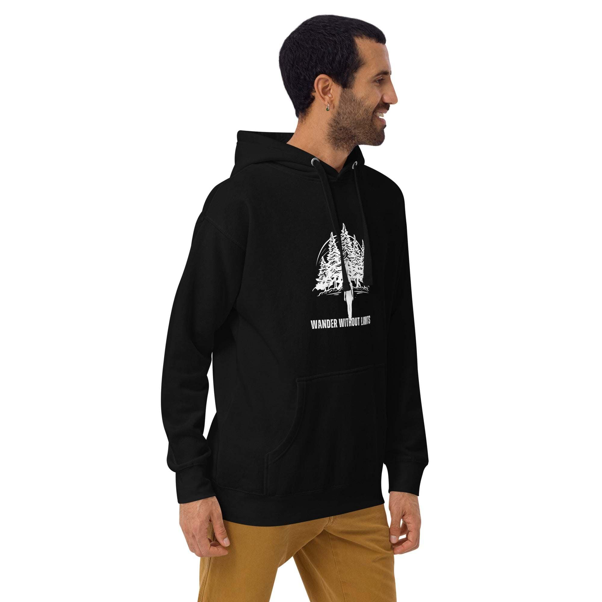 Man wearing black Wander Without Limits Hoodie with wilderness tree graphic, paired with brown pants, side view