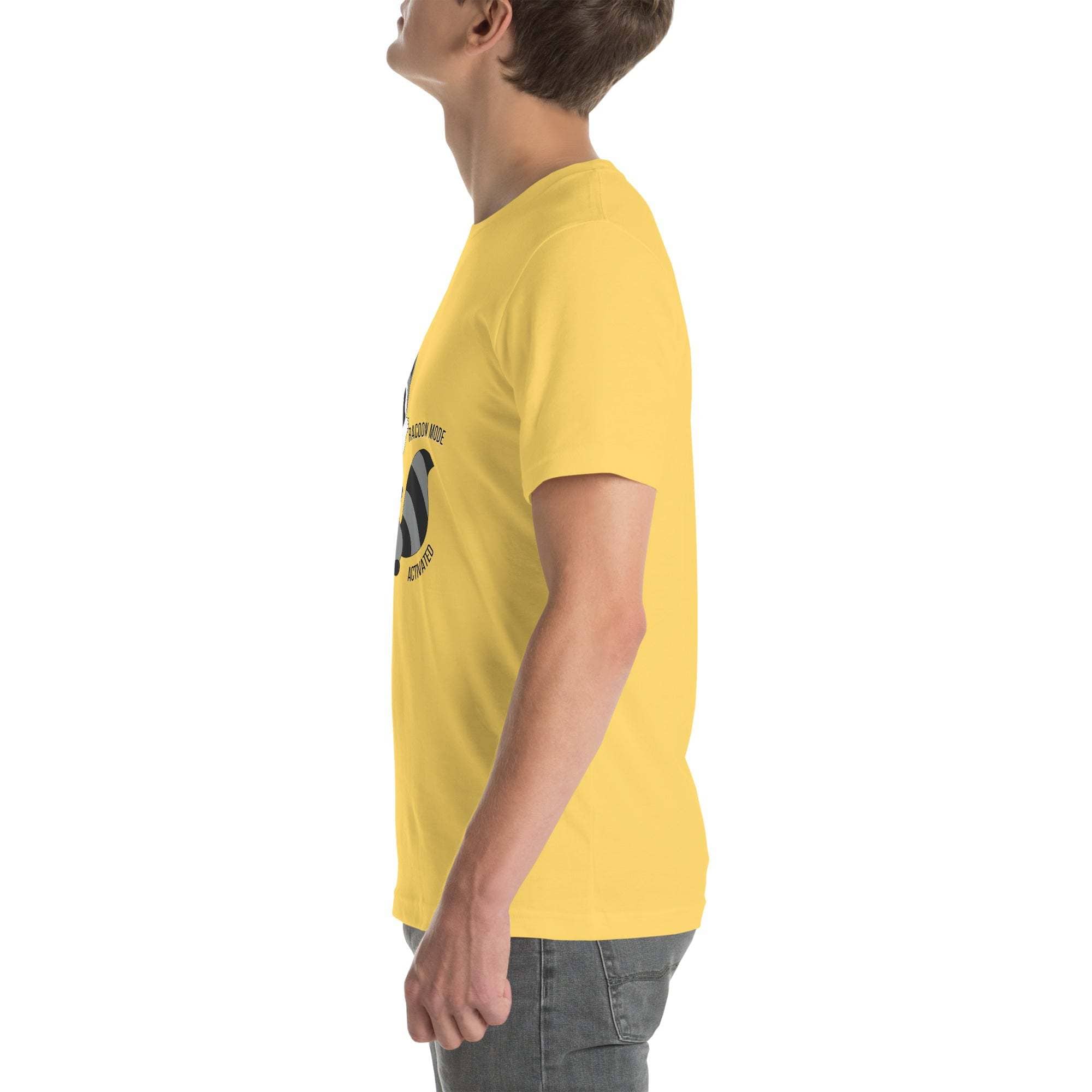 Side view of a man wearing a yellow Raccoon Mode T-Shirt with cartoon raccoon and text design