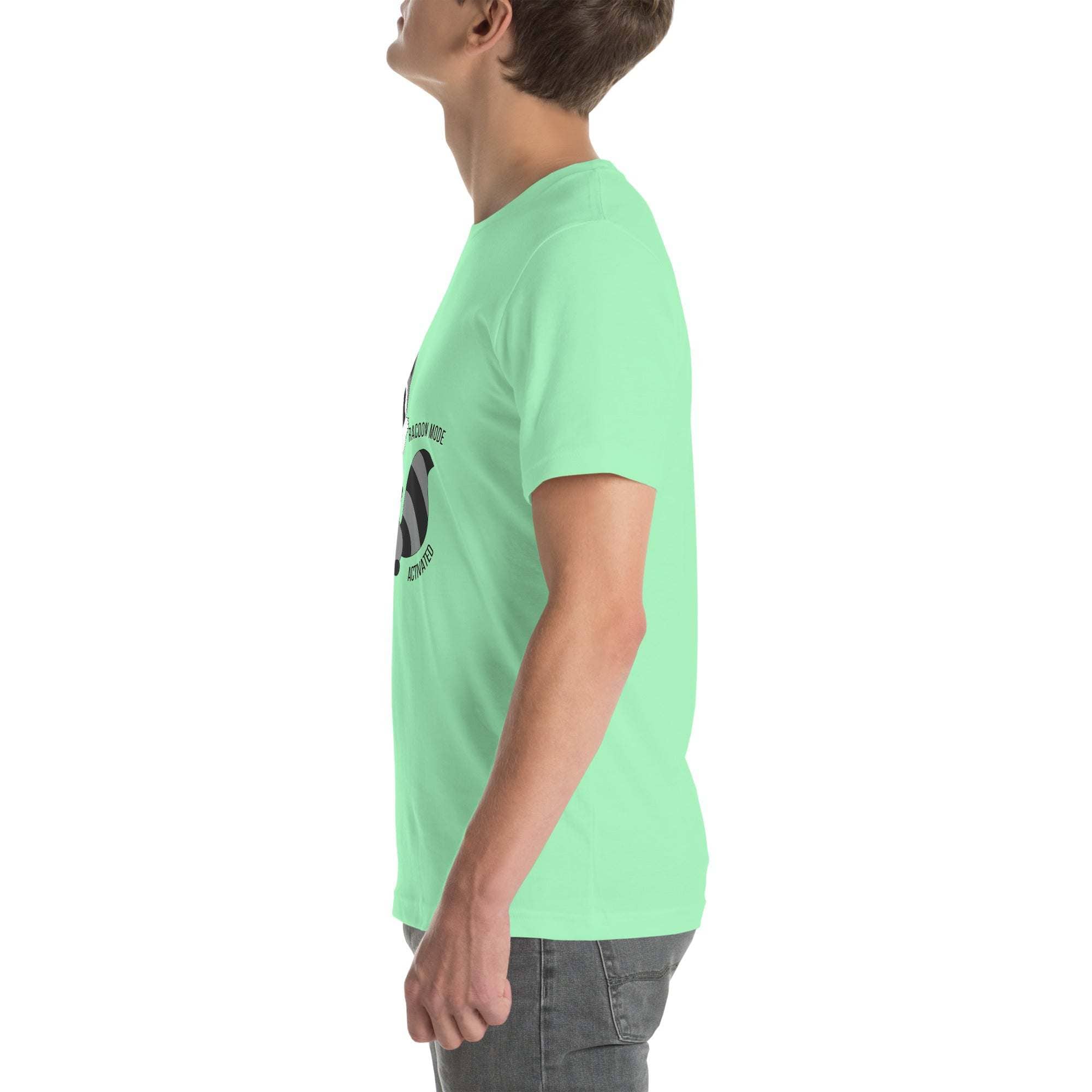 Side view of a person wearing a light green Raccoon Mode T-Shirt with cartoon raccoon design and text on the front