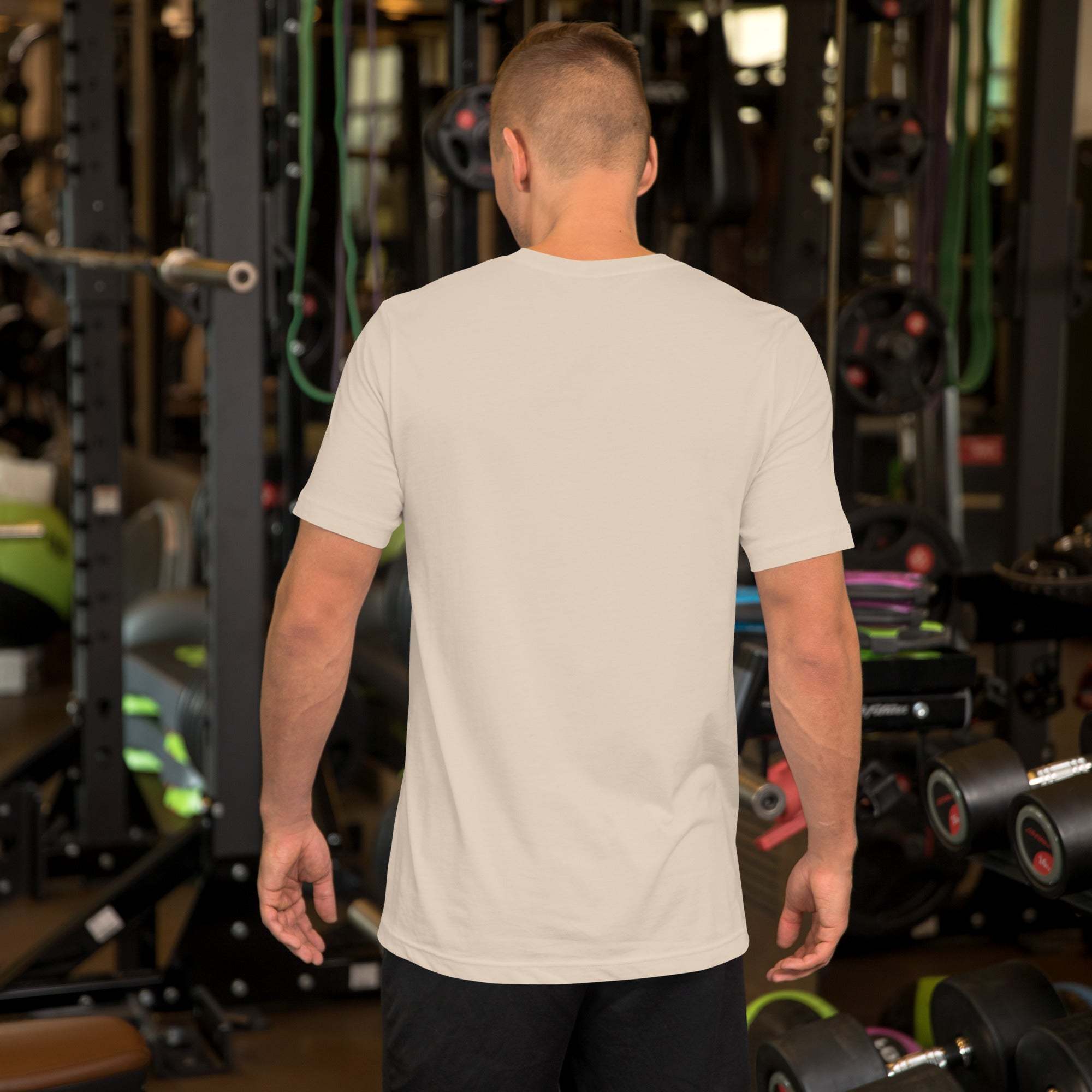 Man wearing plain white Father's Day T-Shirt standing in gym with weightlifting equipment in the background