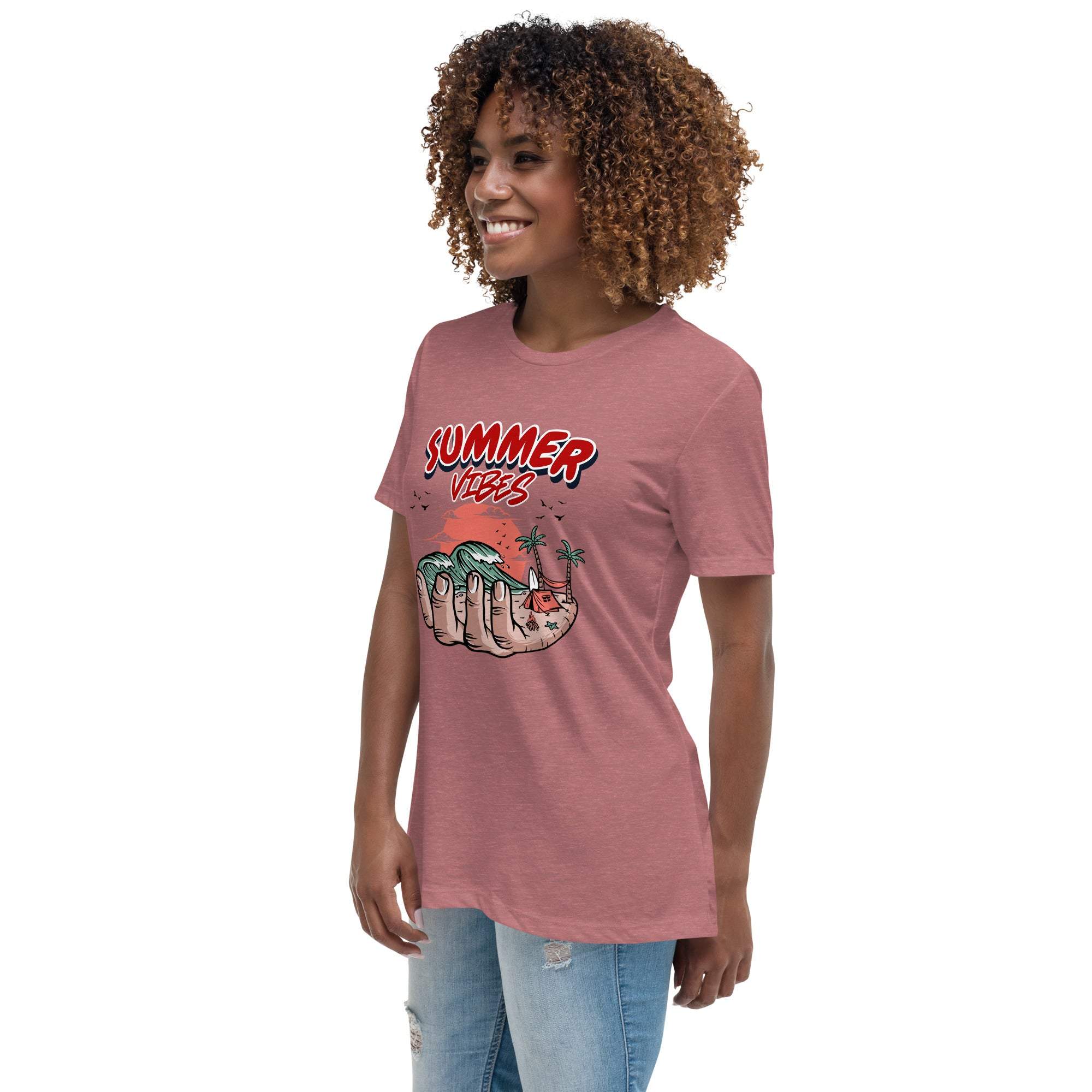 Woman wearing a pink Summer Vibes T-Shirt with a retro beach graphic of a hand holding waves and palm trees, paired with light blue ripped jeans.