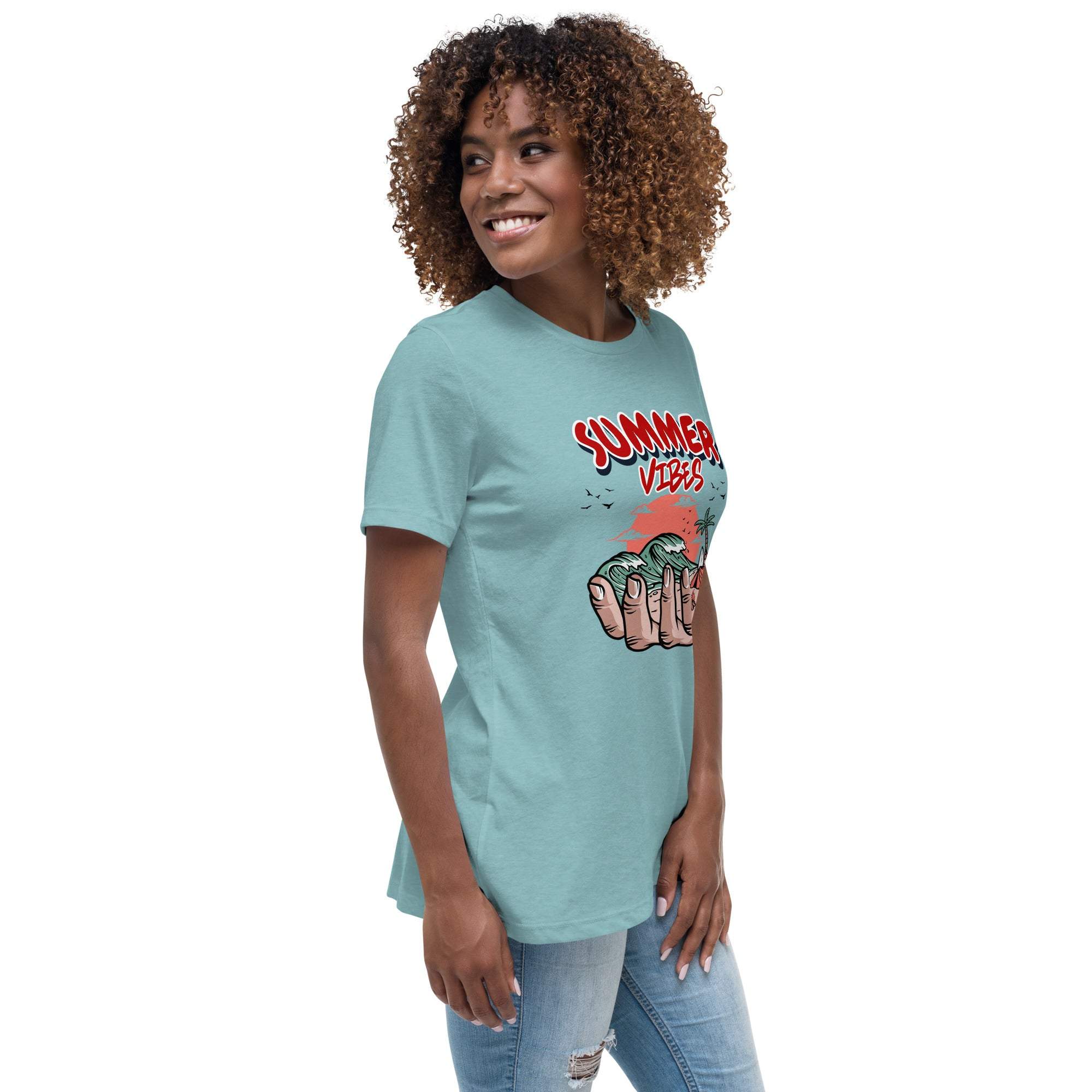 Woman wearing light blue Summer Vibes T-Shirt with retro beach graphic held in a hand, styled with casual jeans.