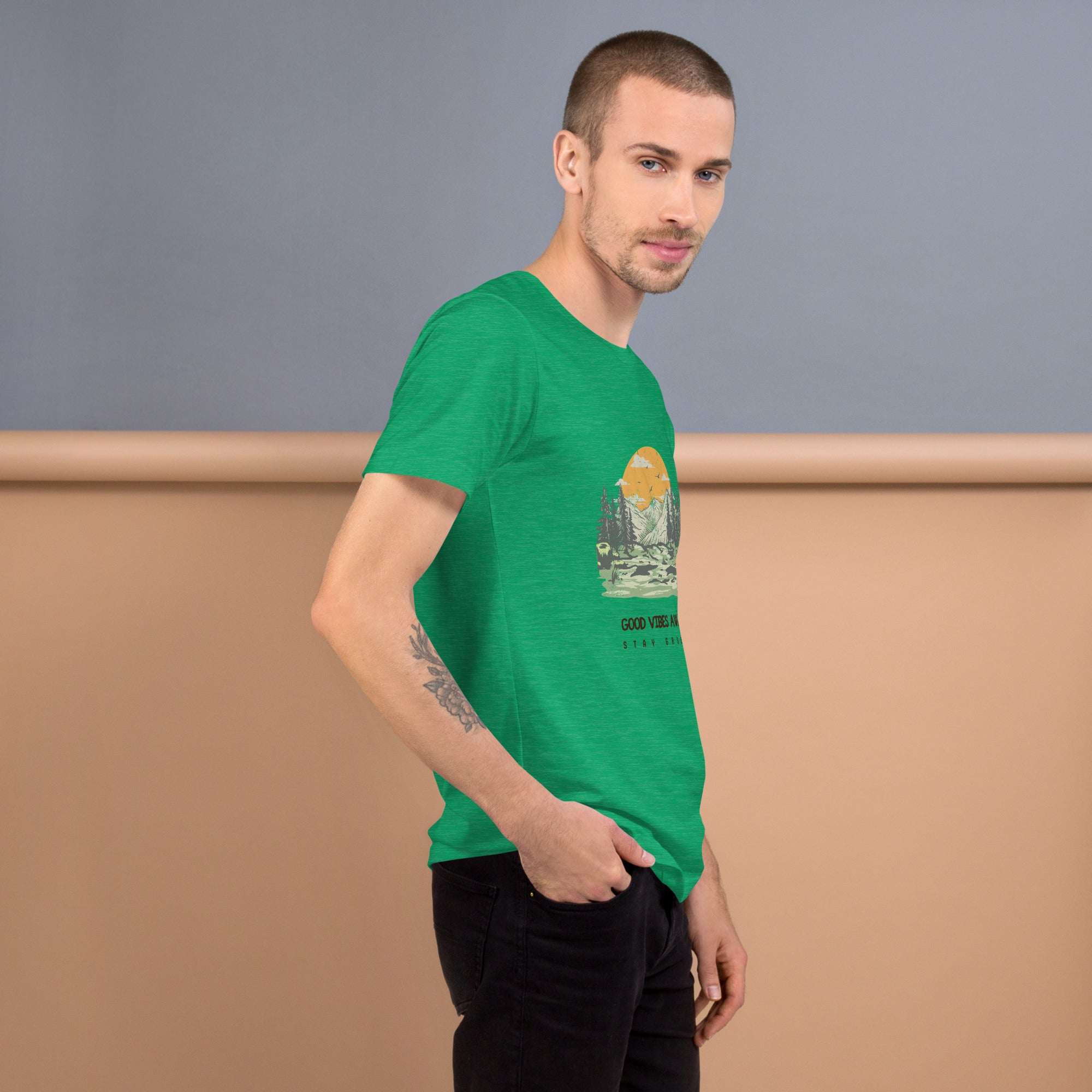 Man wearing green Good Vibes T-Shirt with nature graphic and sunset design