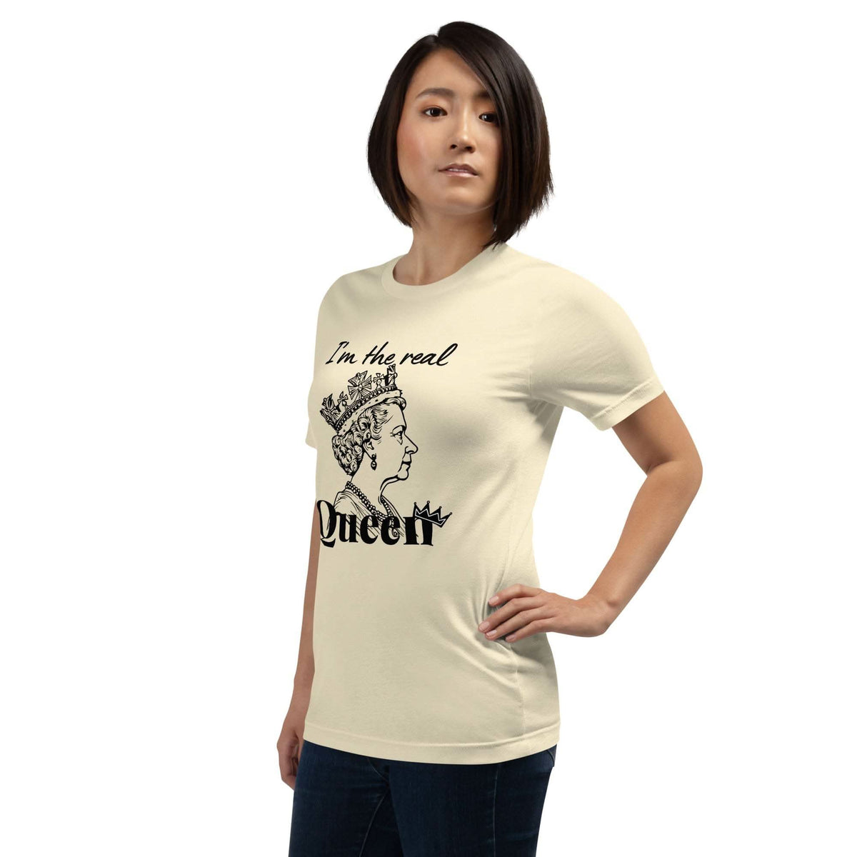 Woman wearing beige "I'm the Real Queen" T-shirt with queen crown graphic and bold text, styled casually