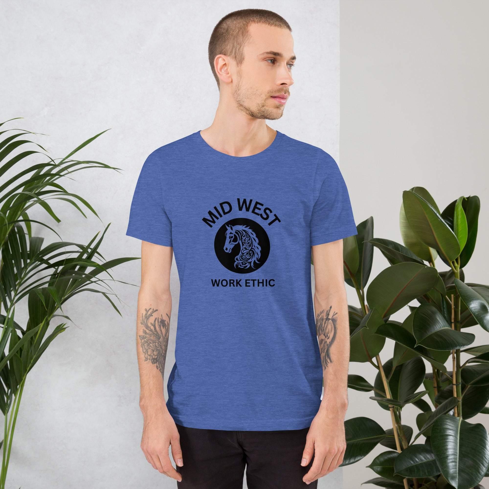 Man wearing blue Midwest work ethic t-shirt with black horse graphic and text in indoor plant setting
