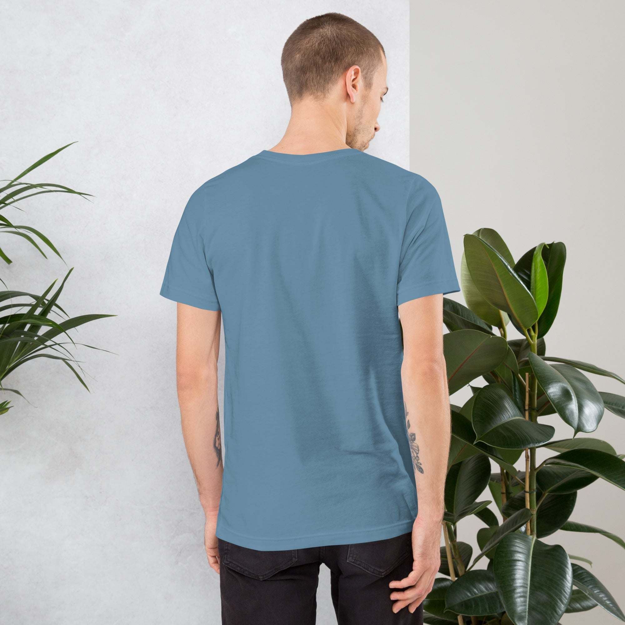 Back view of man wearing plain blue Midwest T-shirt standing near green plants indoors