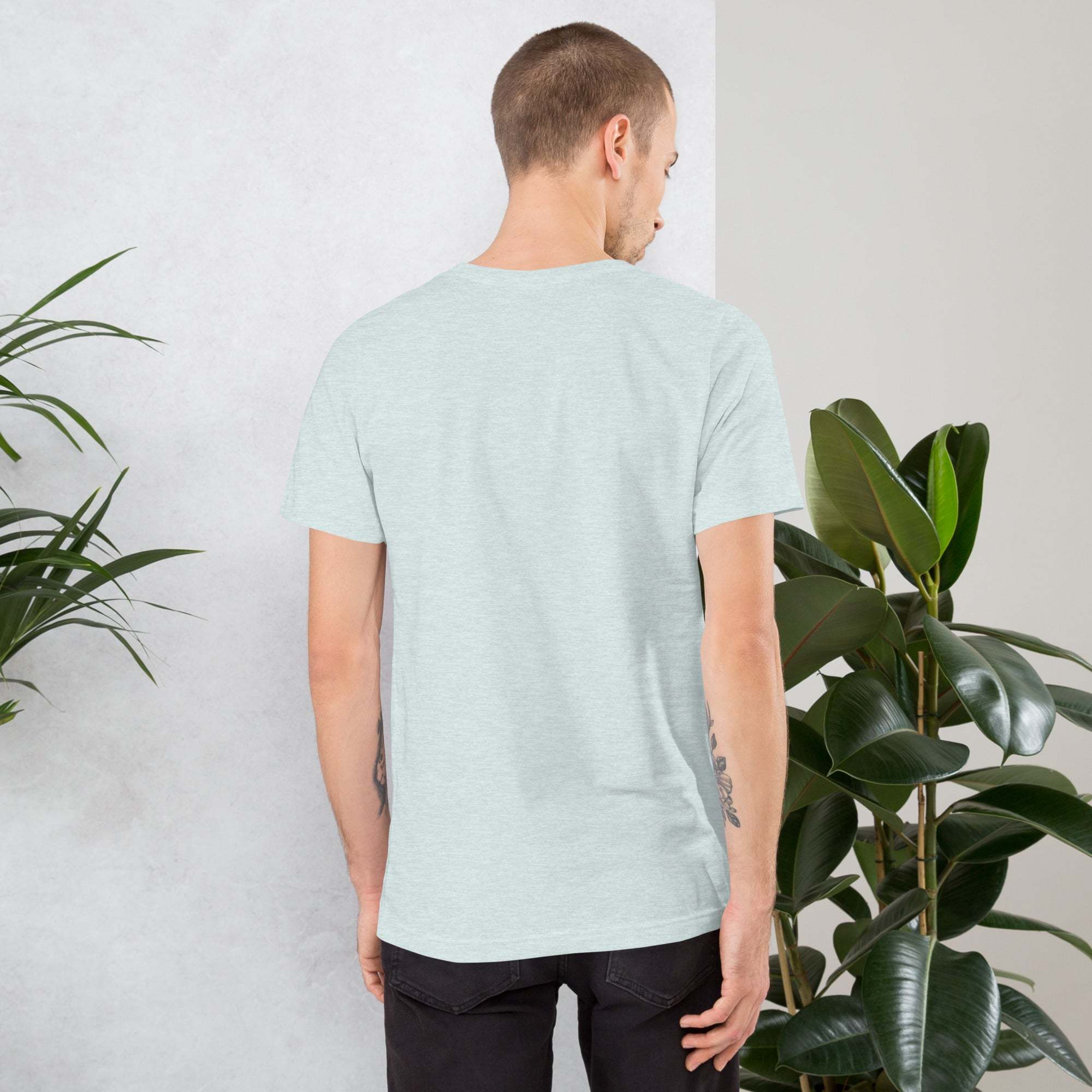 Back view of man wearing light gray Midwest T-Shirt with short sleeves standing near green plants