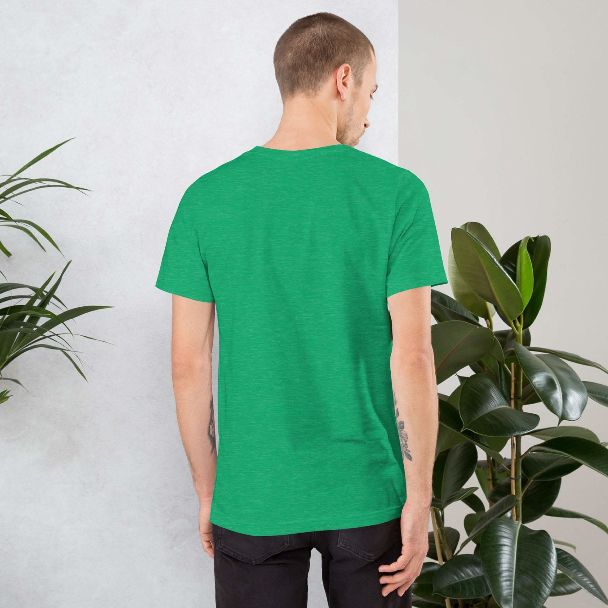 Back view of man wearing plain green vintage aesthetic frog and mushroom t-shirt standing near indoor plants