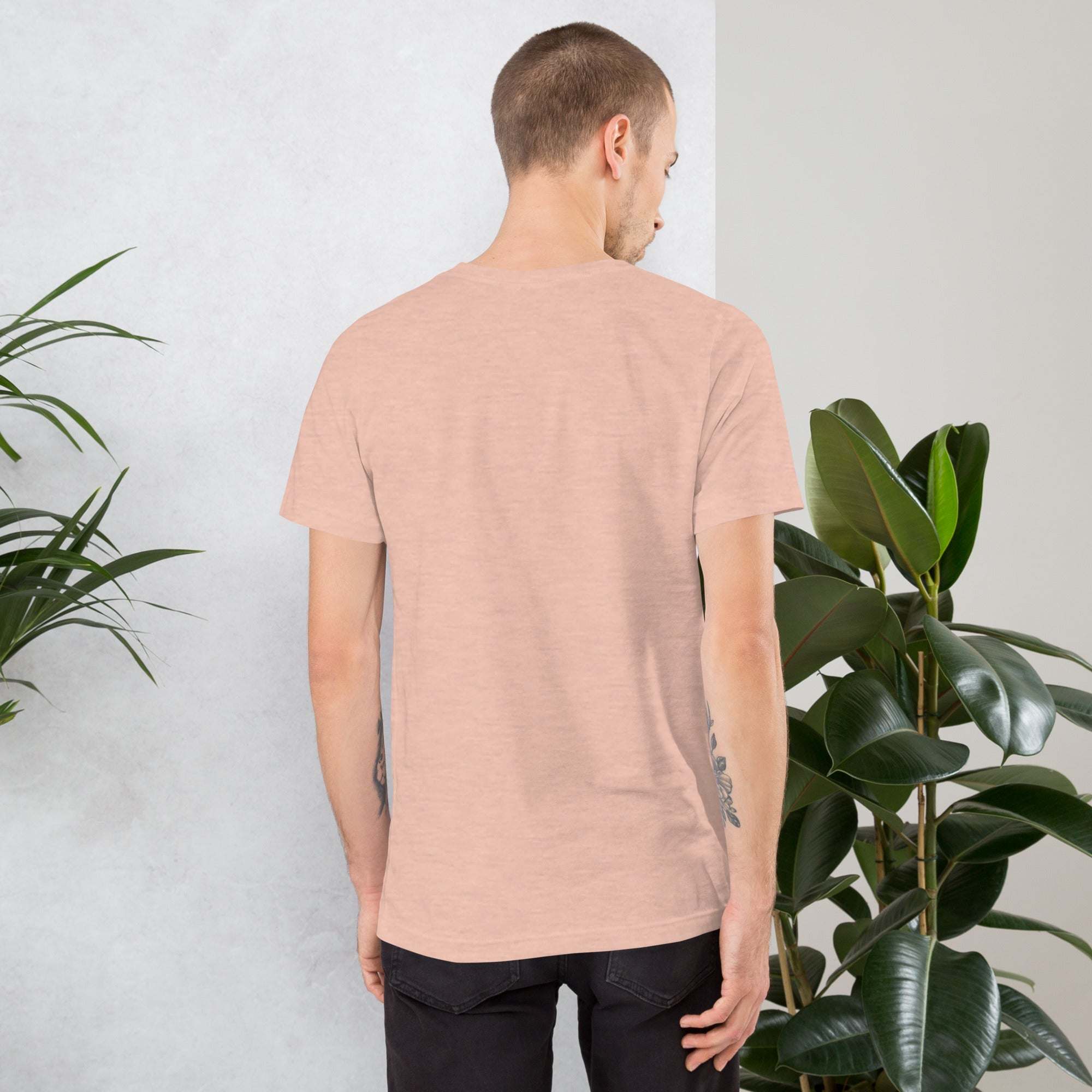 Back view of a man wearing a soft cotton vintage aesthetic frog and mushroom t-shirt in light pink color.