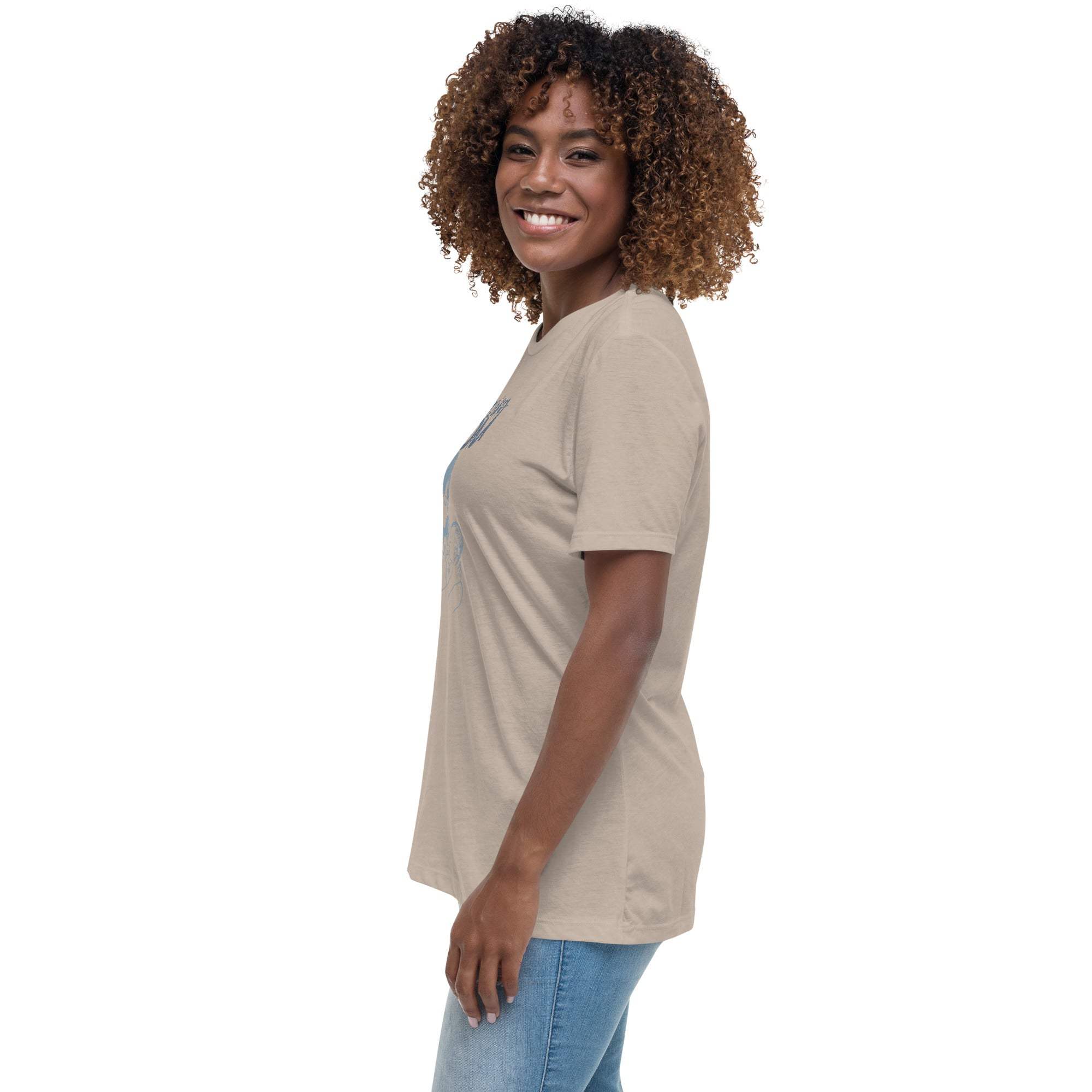 Smiling woman wearing a beige Amazing Mom T-Shirt and blue jeans standing sideways against a white background