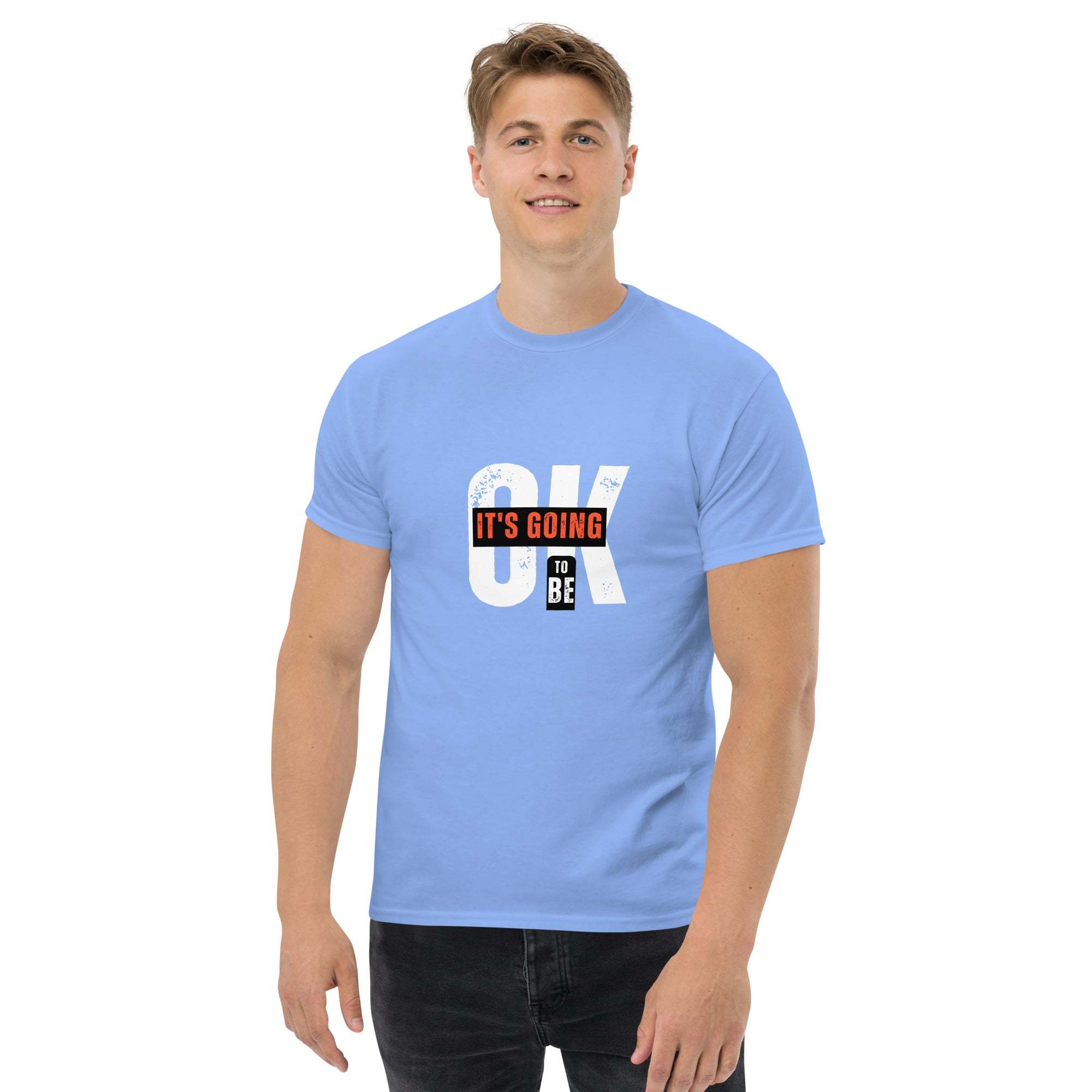 Man wearing a light blue trendy graphic t-shirt with motivational quote "OK It's Going To Be" printed on front, casual streetwear summer style