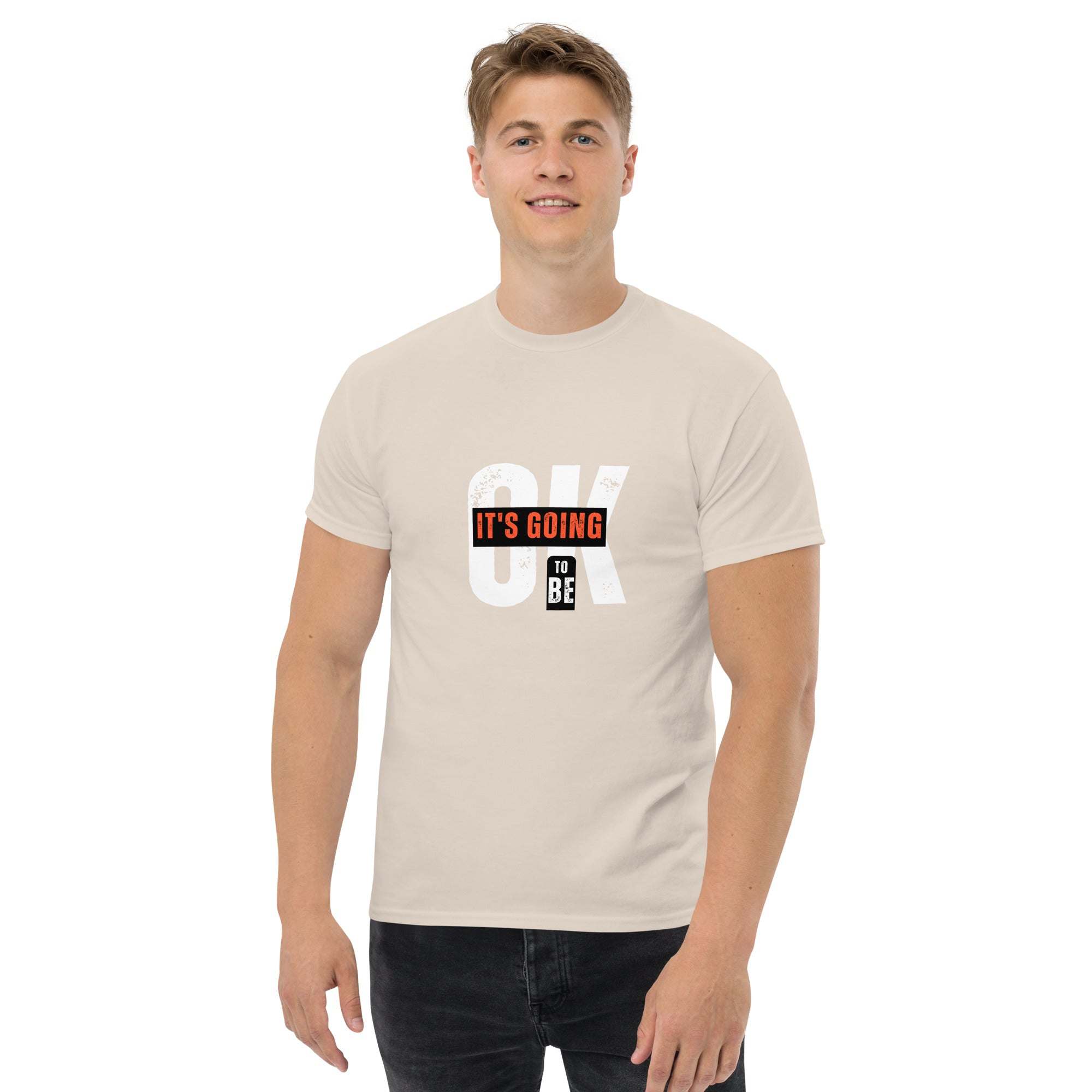 Man wearing beige trendy graphic t-shirt with motivational quote "IT'S GOING TO BE OK" in street style design