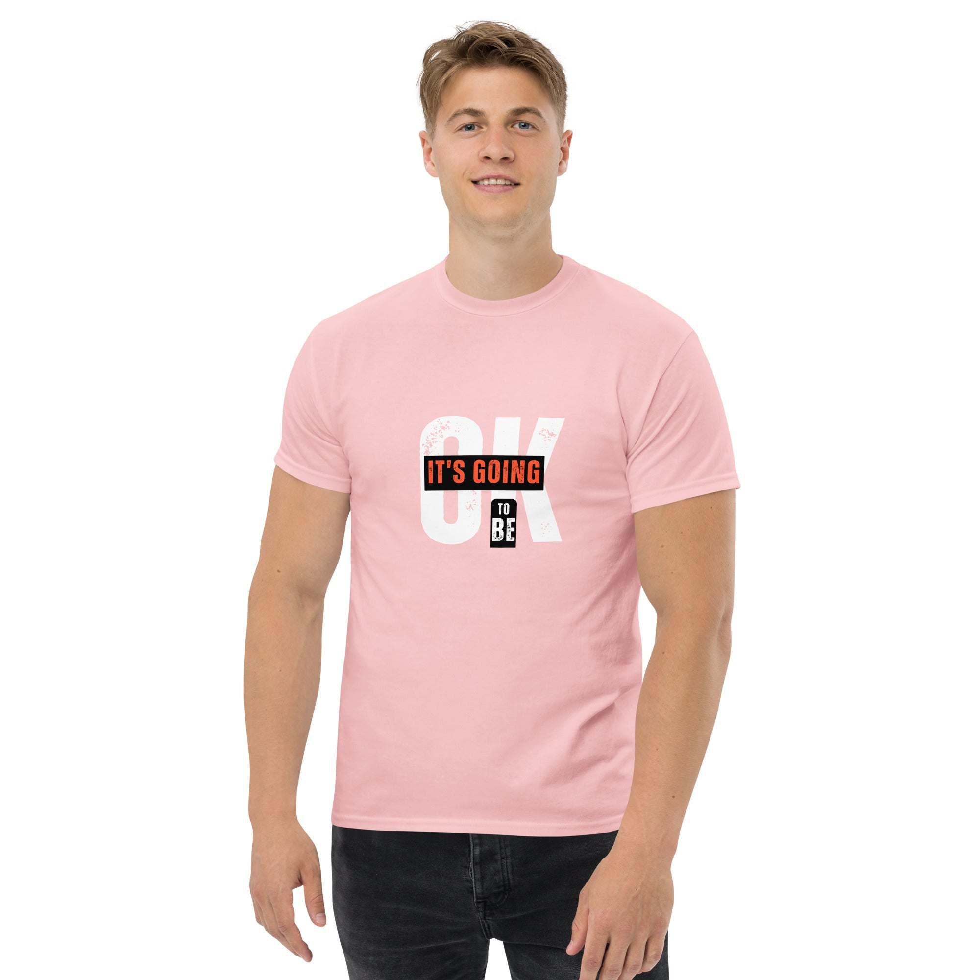 Young man wearing pink trendy graphic t-shirt with motivational "It's going to be OK" print in casual summer style