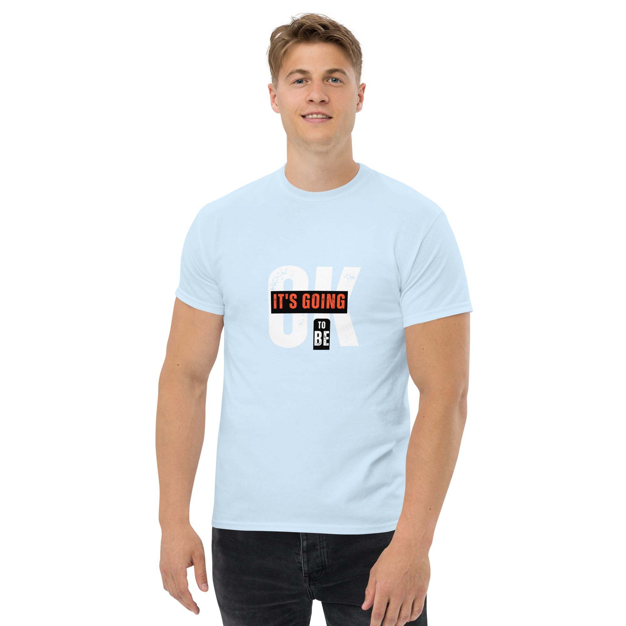 Man wearing light blue trendy graphic t-shirt with motivational quote "OK It's Going To Be" in casual streetwear style