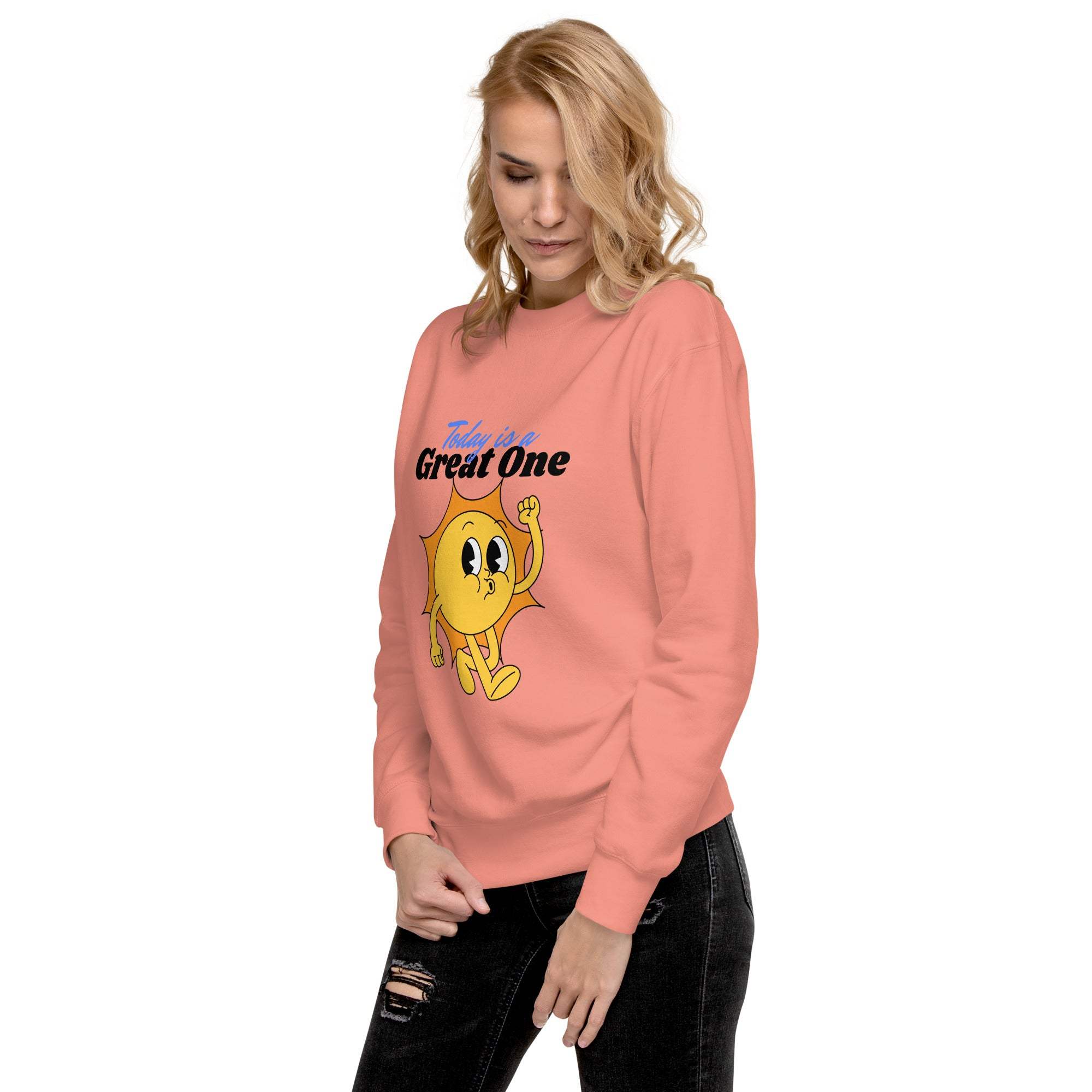 Woman wearing a coral Positive Sun Sweatshirt with a cheerful sun graphic and motivational text "Today is a Great One"