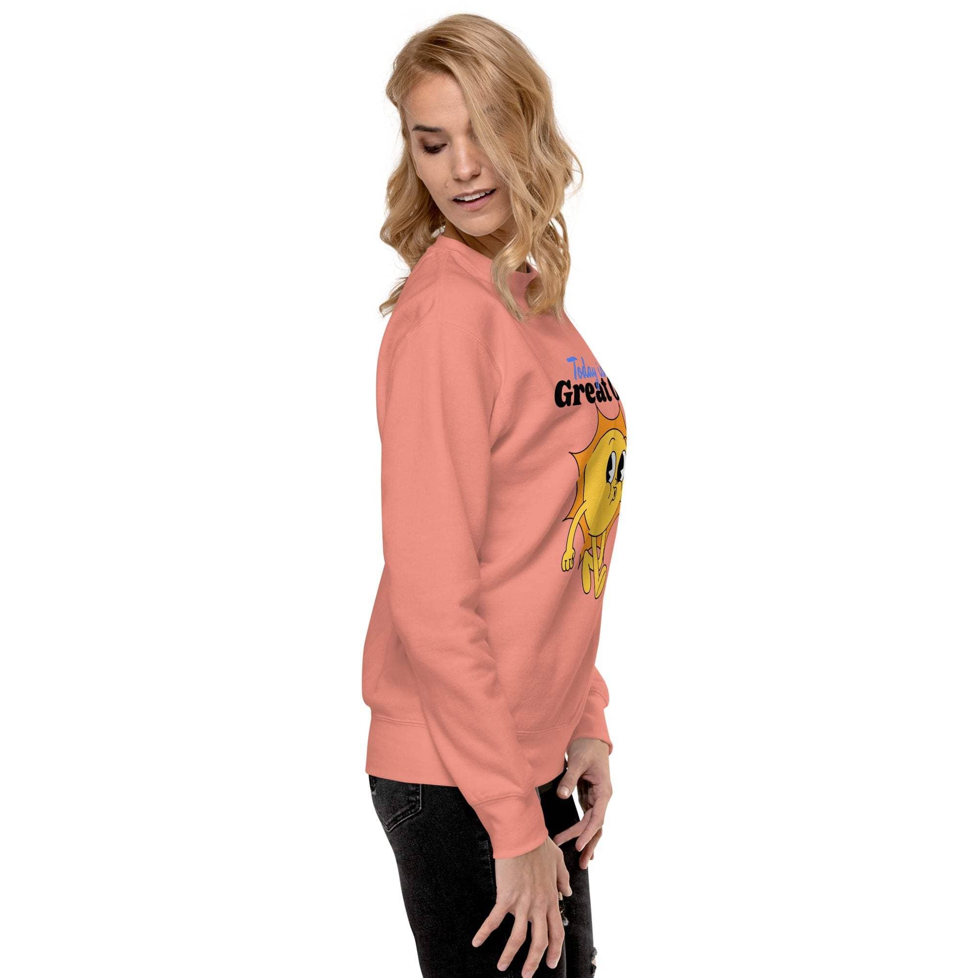 Woman wearing a coral Positive Sun Sweatshirt with a happy sunshine graphic and motivational text, styled casually with black pants.
