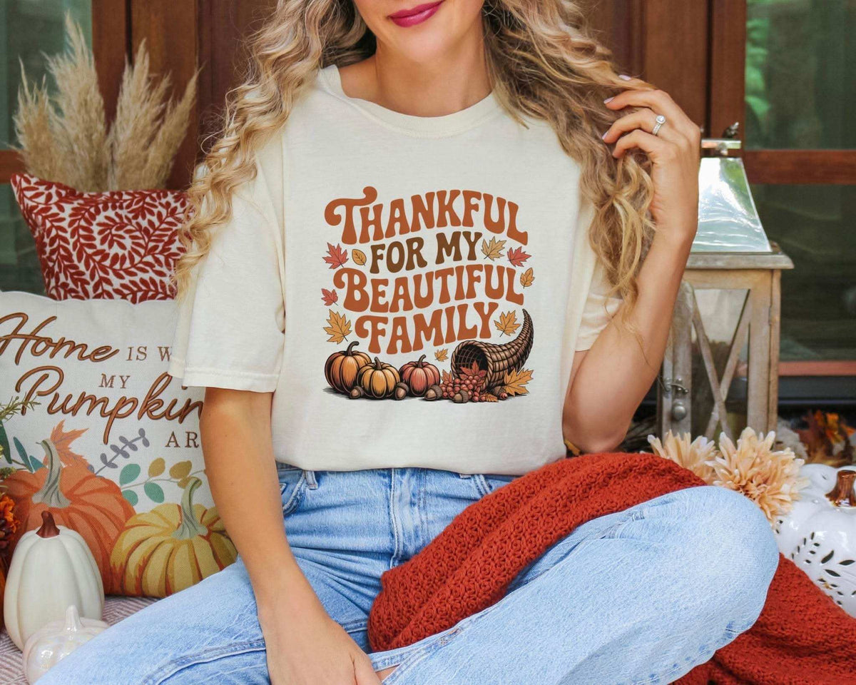 Model wearing an ivory Thankful for My Beautiful Family graphic T-shirt with jeans in an autumn setting.