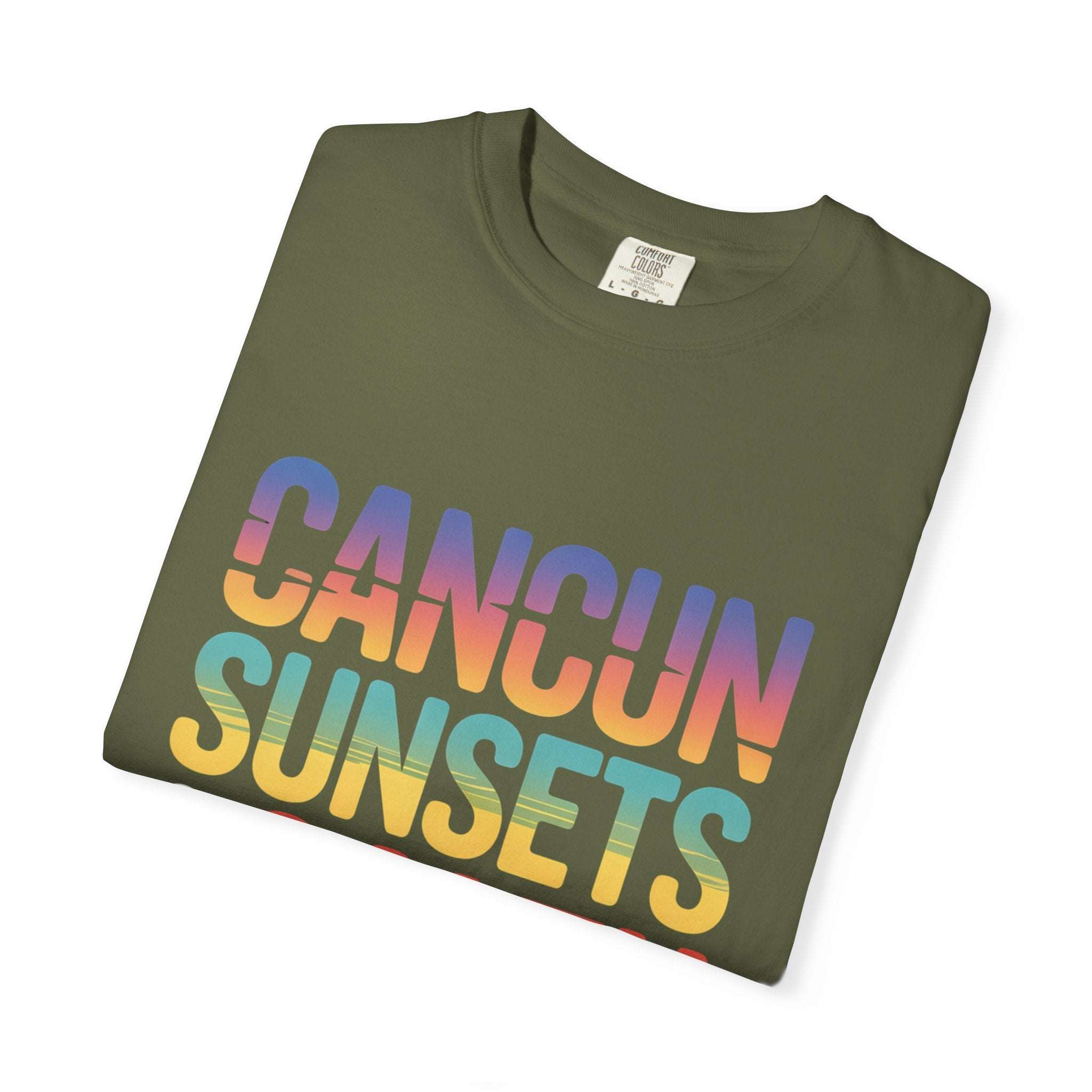 Folded green t-shirt with 'Cancun Sunsets' text in rainbow colors on a white background