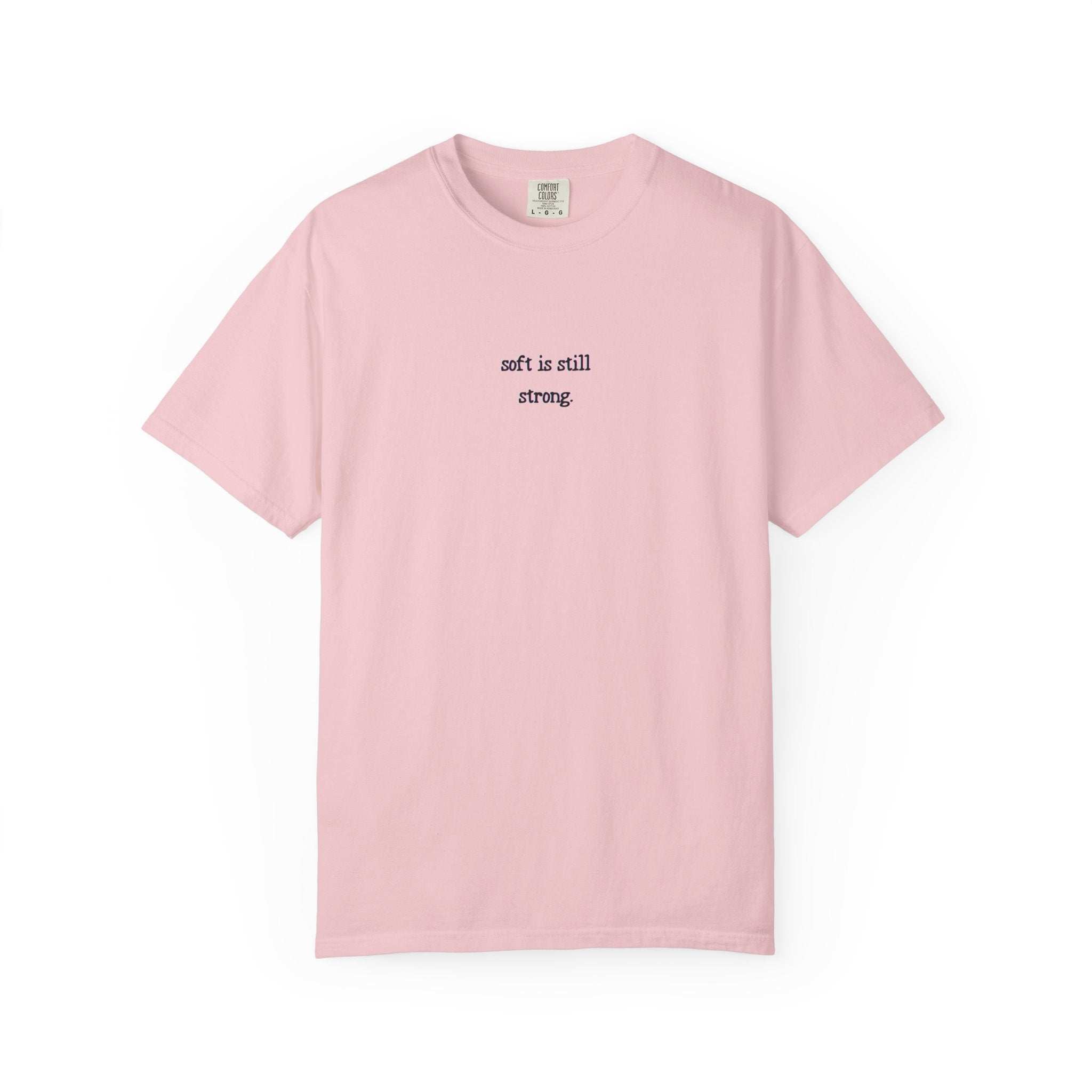 Pink t-shirt with text 'soft is still strong' on a white background