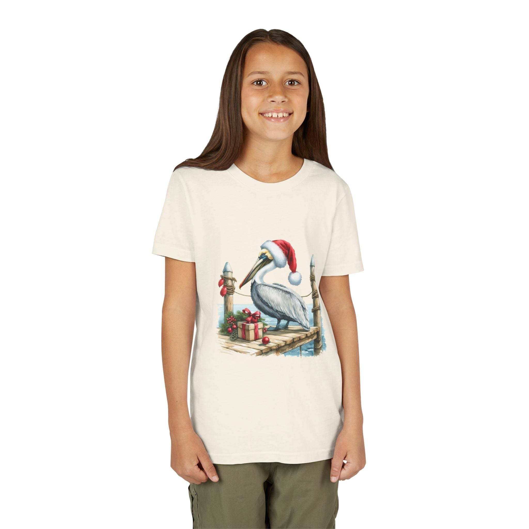 Youth t-shirt featuring pelican wearing Santa hat on coastal pier with gifts and nautical elements