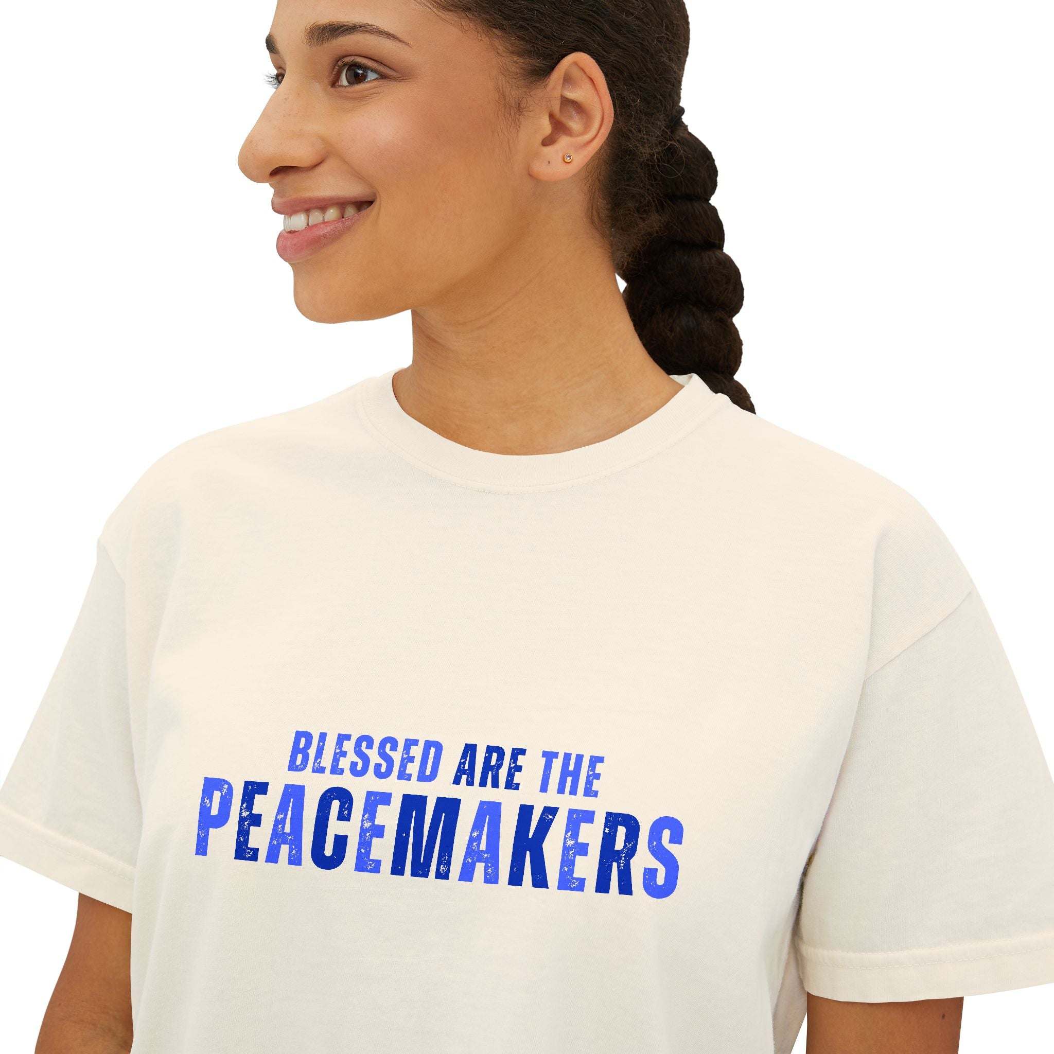 Woman wearing a white Tee Blessed be the Peacemakers women's boxy shirt with blue text promoting peace and harmony