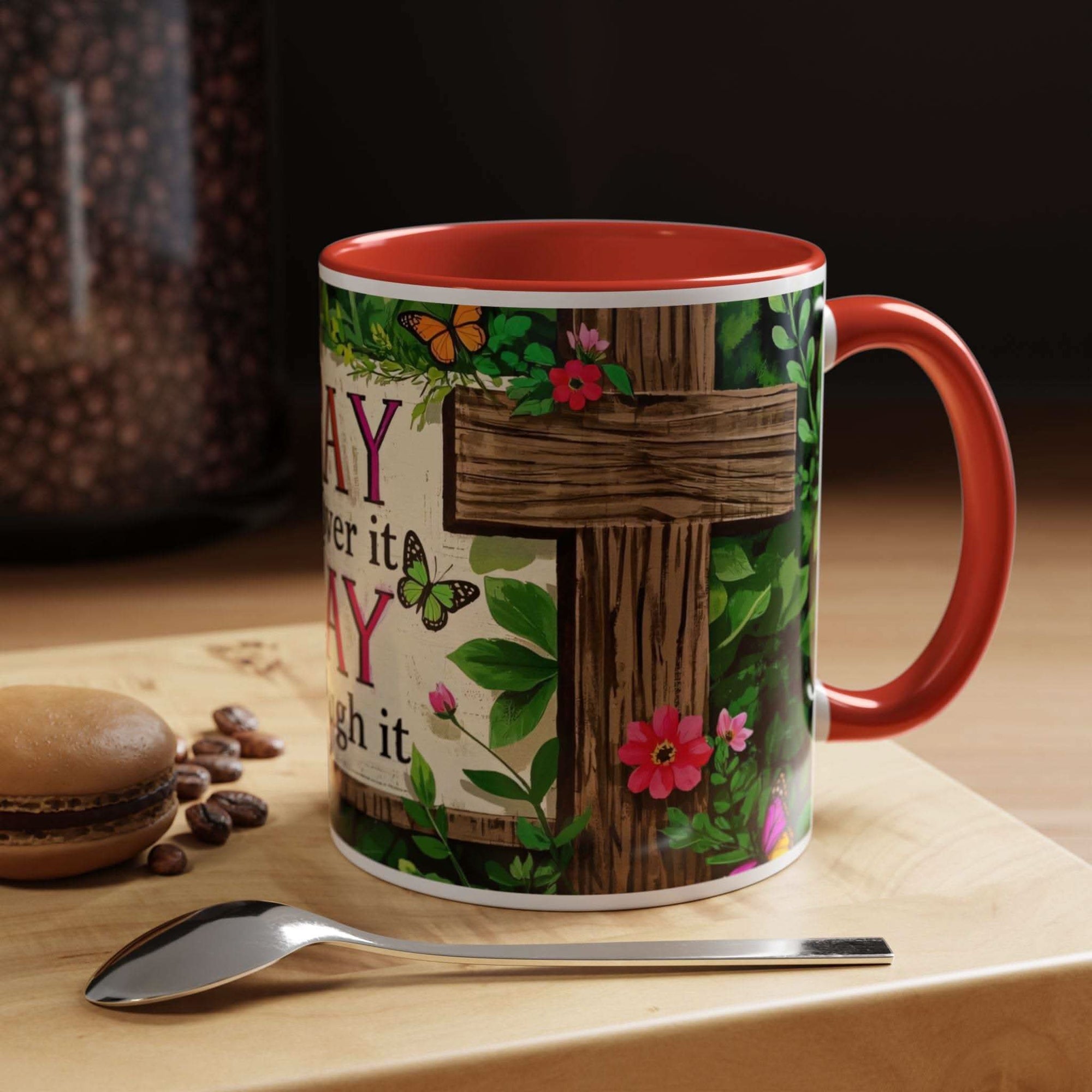 Mug with floral and wooden cross design on a table with coffee beans and a spoon.