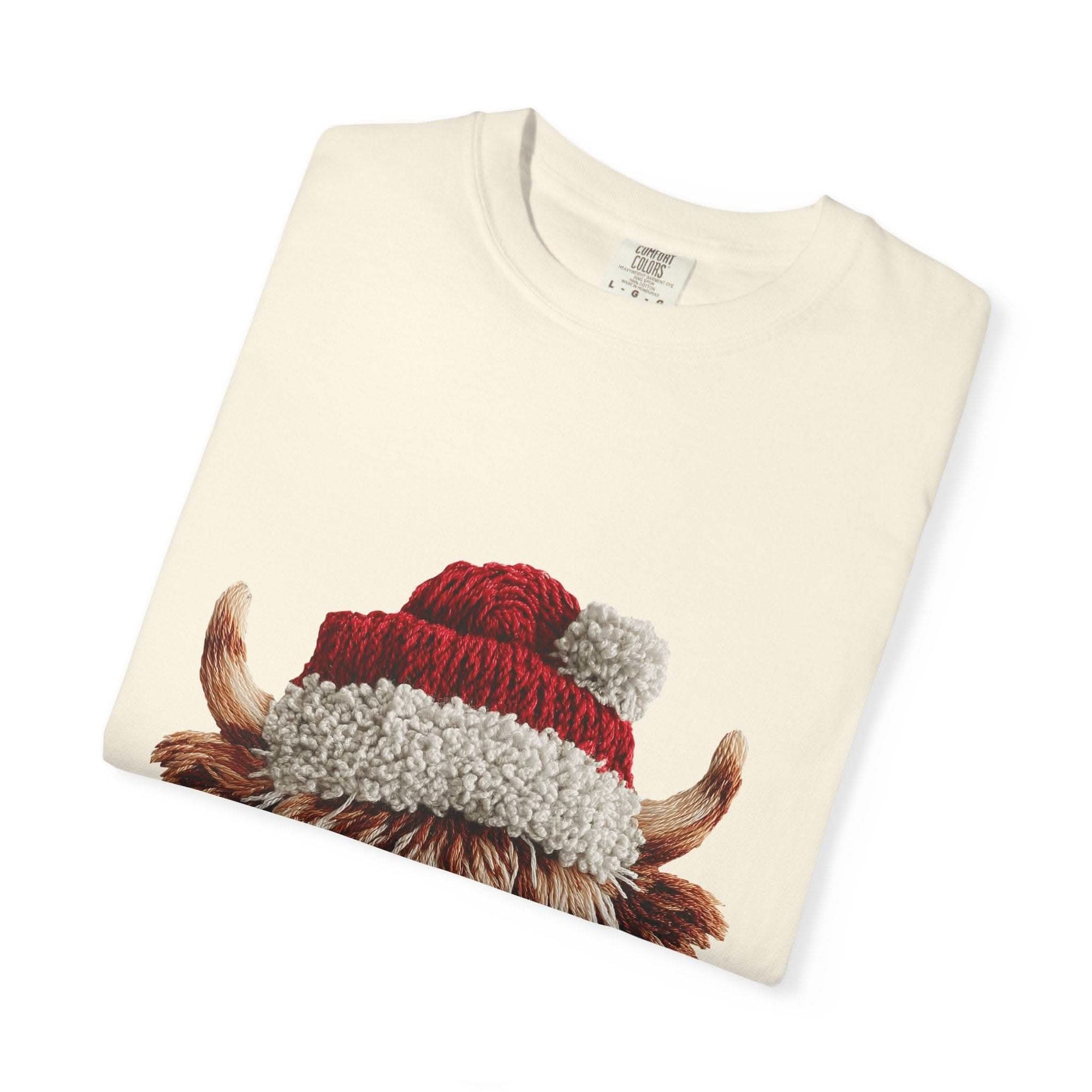 Cream T-shirt with faux crochet yarn highland cow wearing Santa hat print