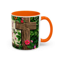 Mug with orange interior and handle, featuring a wooden cross and floral design on a white background