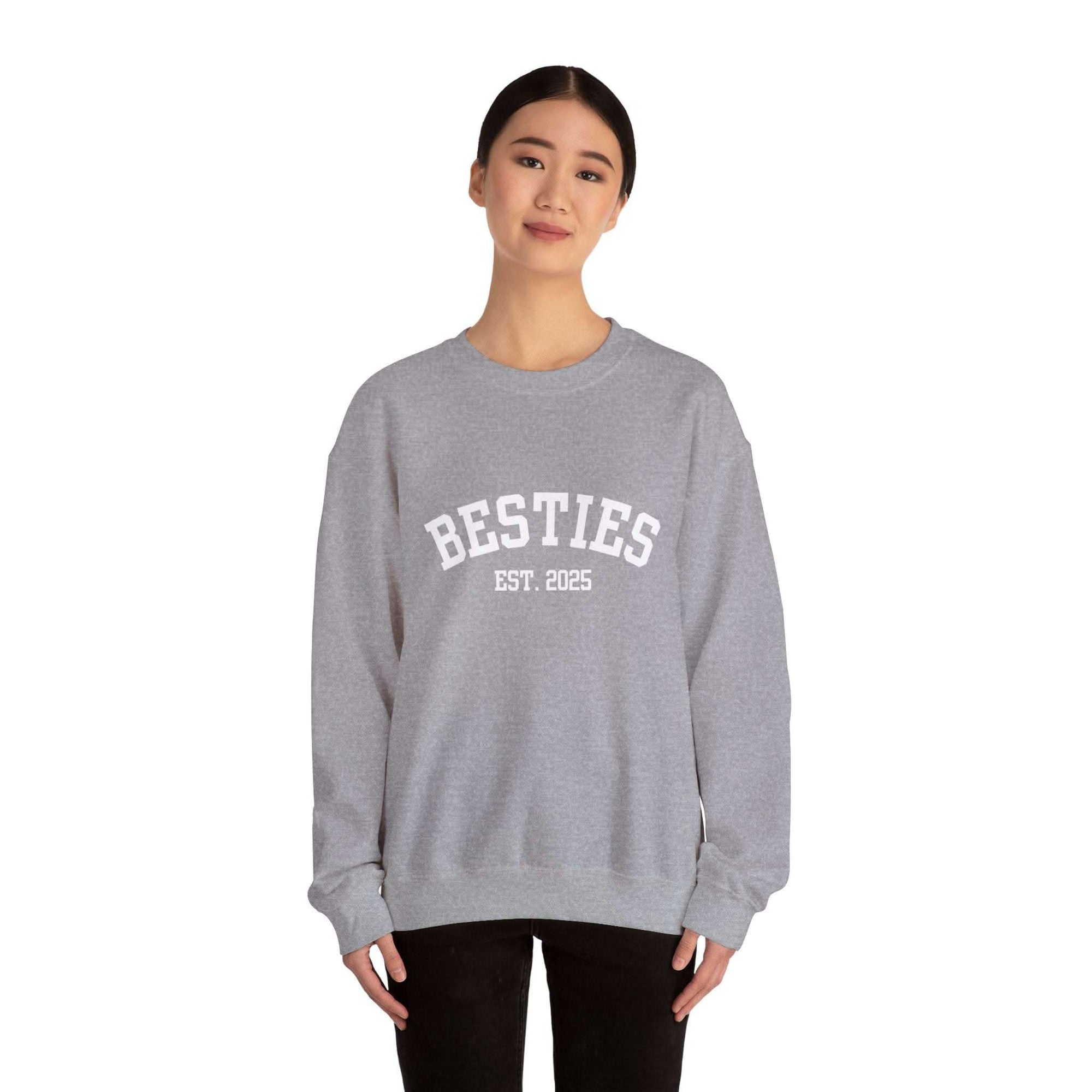 Person wearing a gray sweatshirt with 'BESTIES EST. 2025' text on a white background