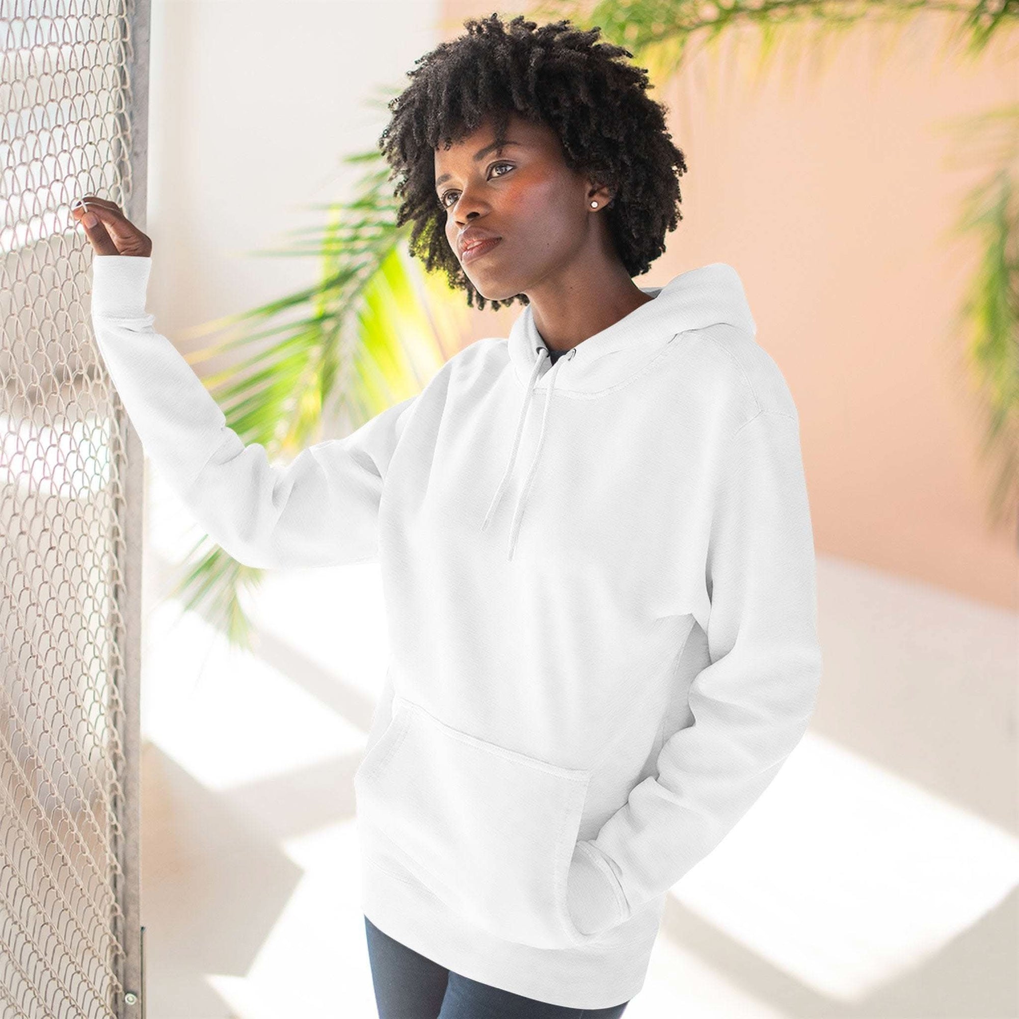 Woman wearing plain white fleece hoodie with adjustable hood and kangaroo pocket in bright indoor setting